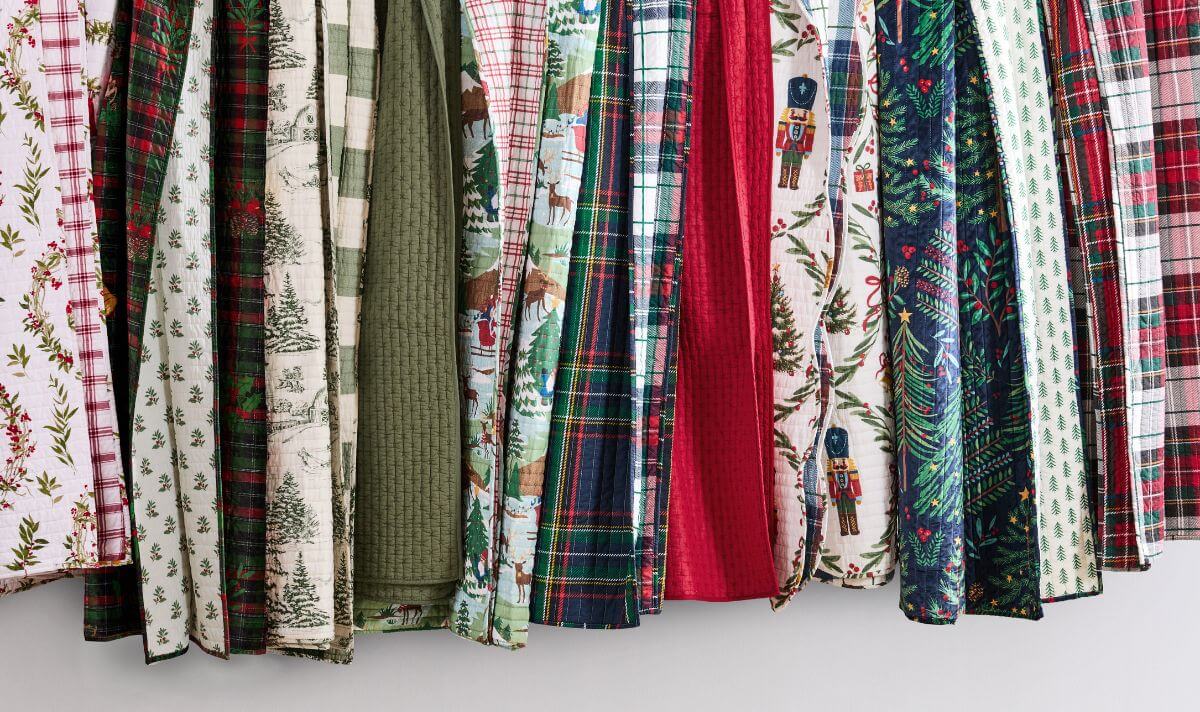 Christmas decorations items list displayed as assorted holiday quilts and comforters in plaid, woodland, nutcracker, and tree motifs for festive home decor