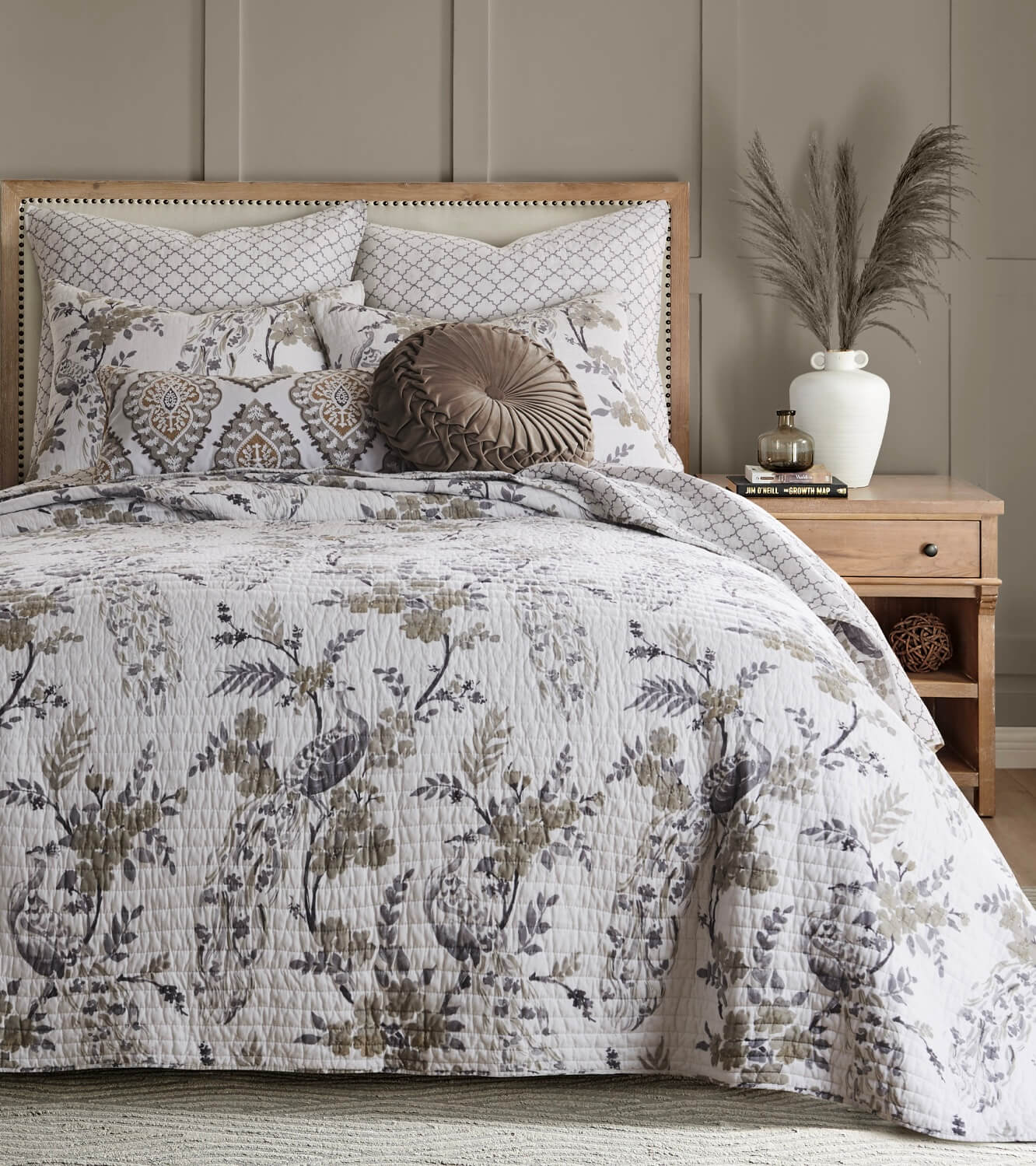 Bed with floral-patterned bedspread set and decorative pillows in a bedroom setting