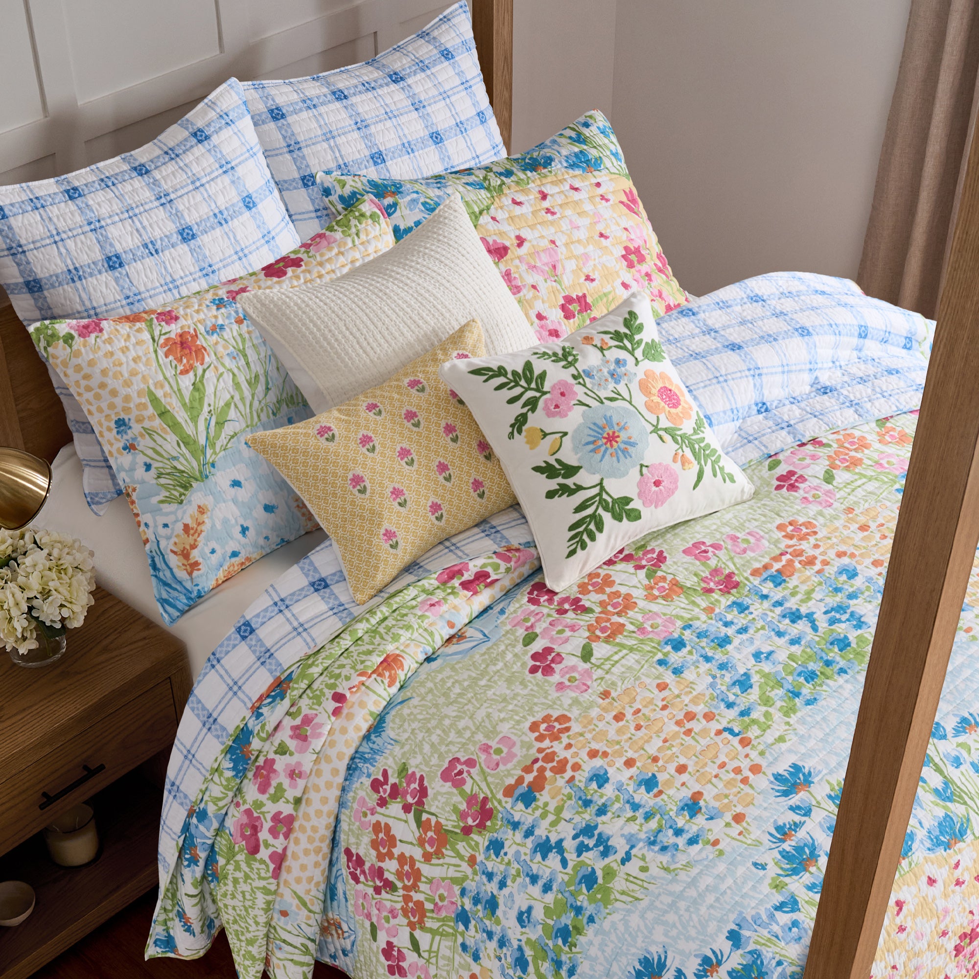 Colorful floral quilt and pillows on a bed in a bedroom setting.