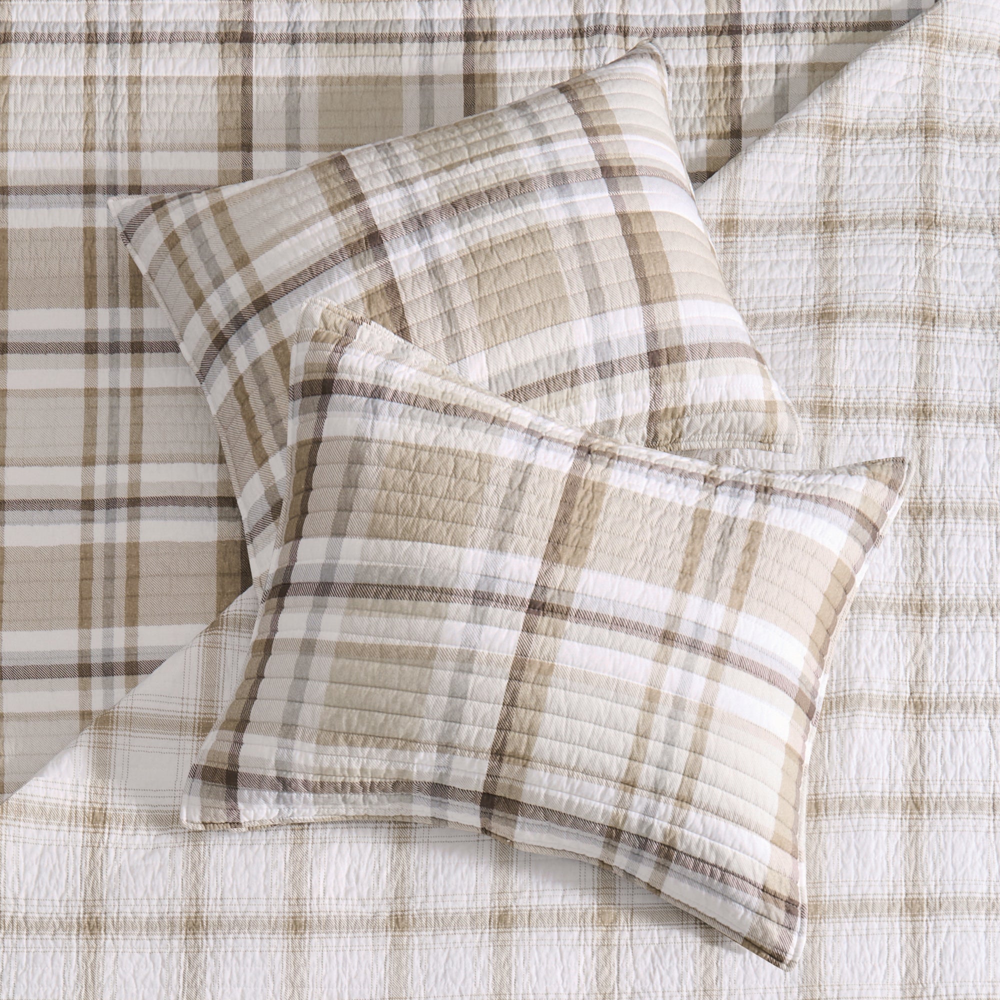 Beige and white plaid Christmas sham set displayed on a matching quilt, featuring soft textured stitching and classic holiday-inspired design.
