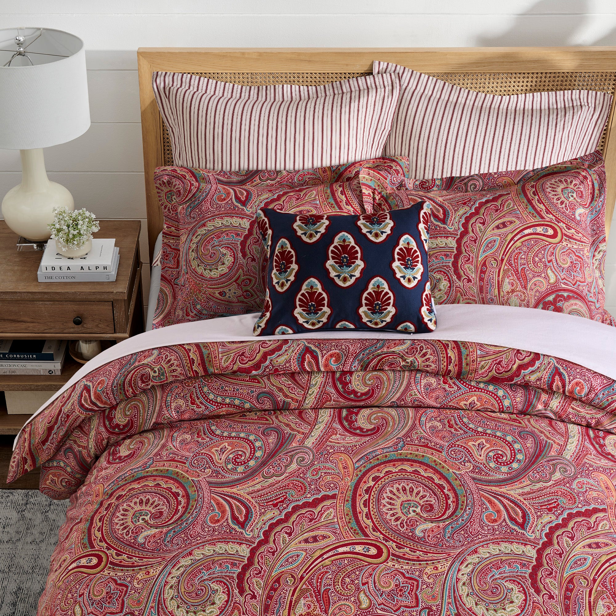 Bed with paisley patterned bedding and pillows in a bedroom setting.