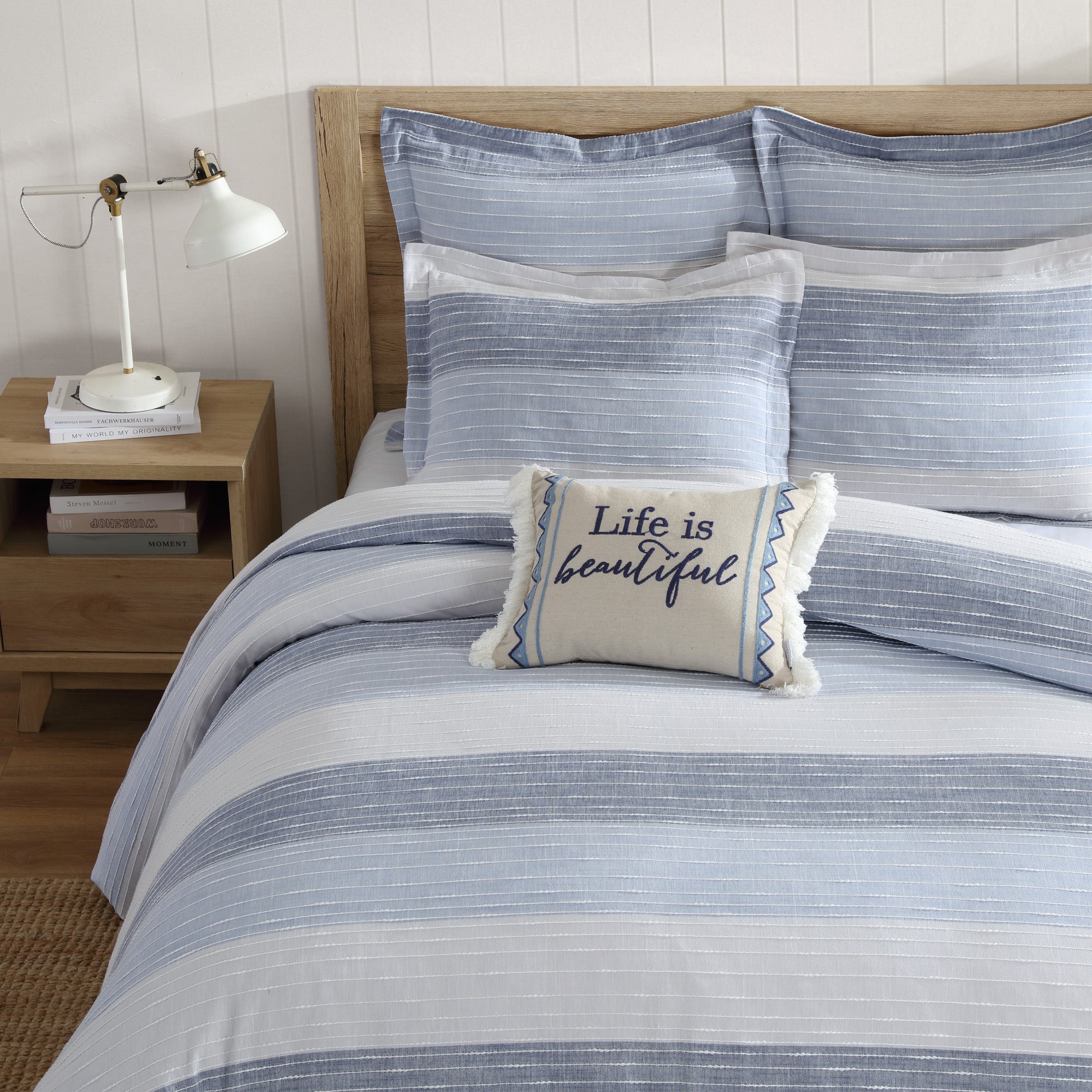 Coastal-style blue and white striped queen comforter set with decorative pillow on wooden bed frame