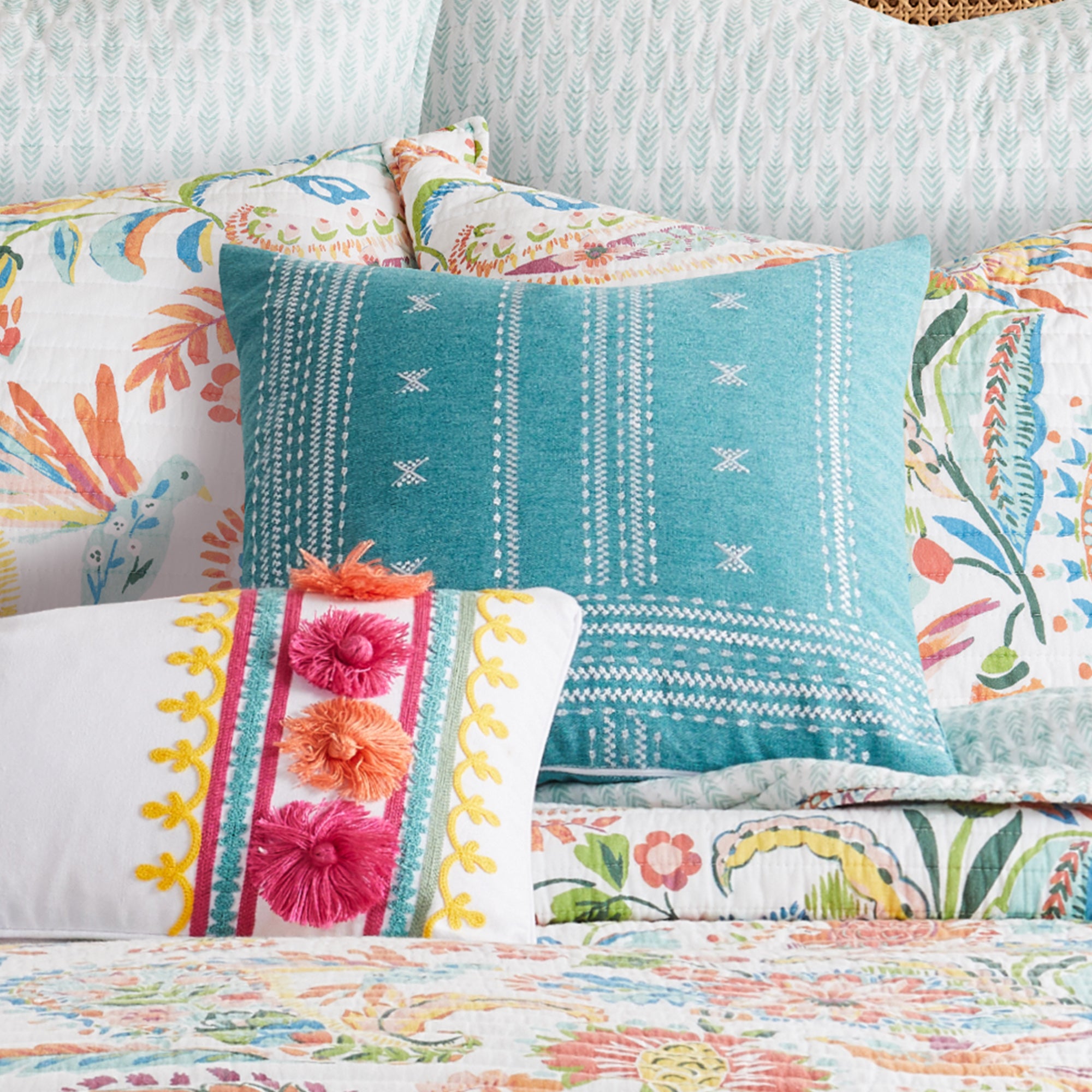 Night Garden Teal Pillow with geometric design on teal fabric, paired with colorful embroidered pillows.