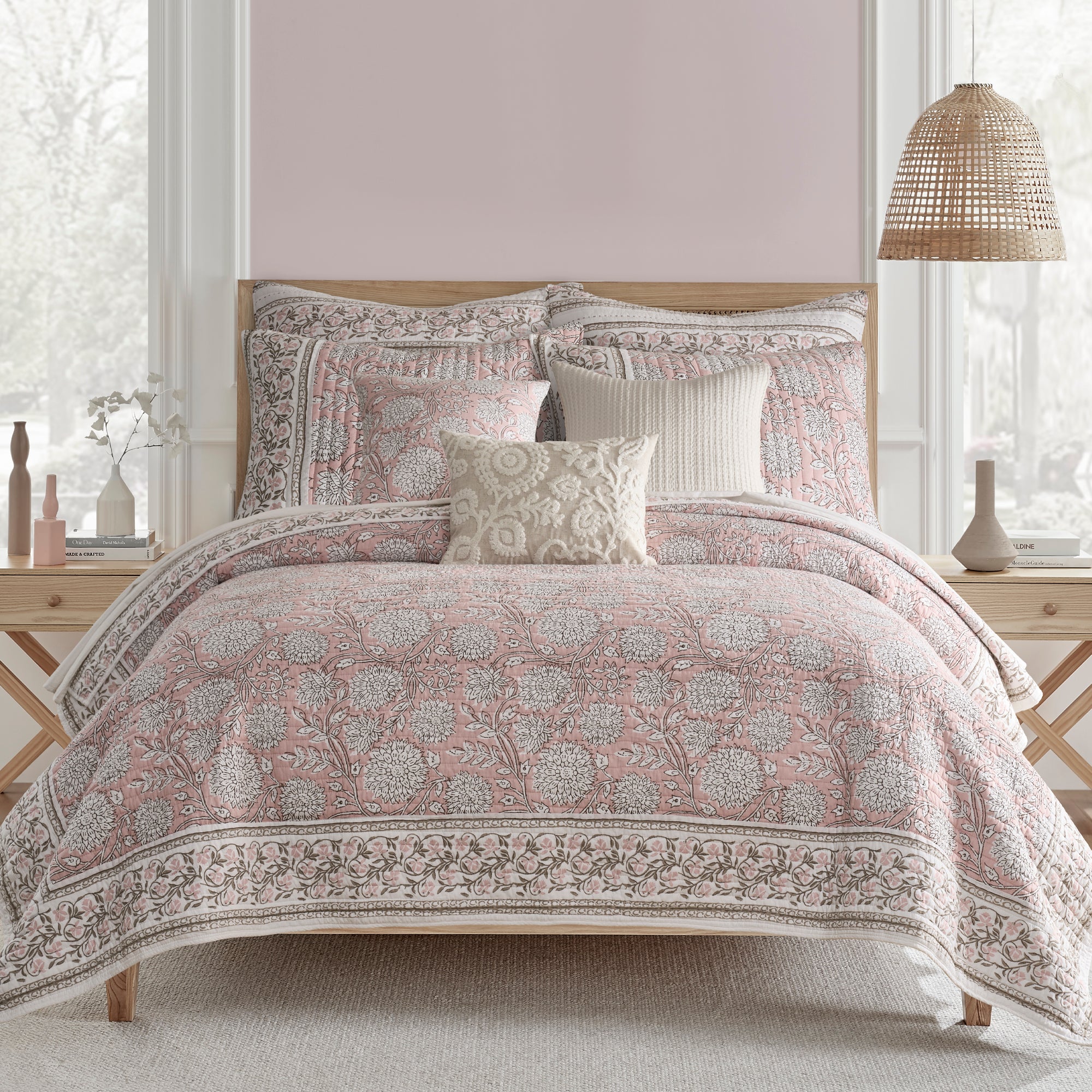 Bed with floral patterned comforter and pillows in a bedroom setting.