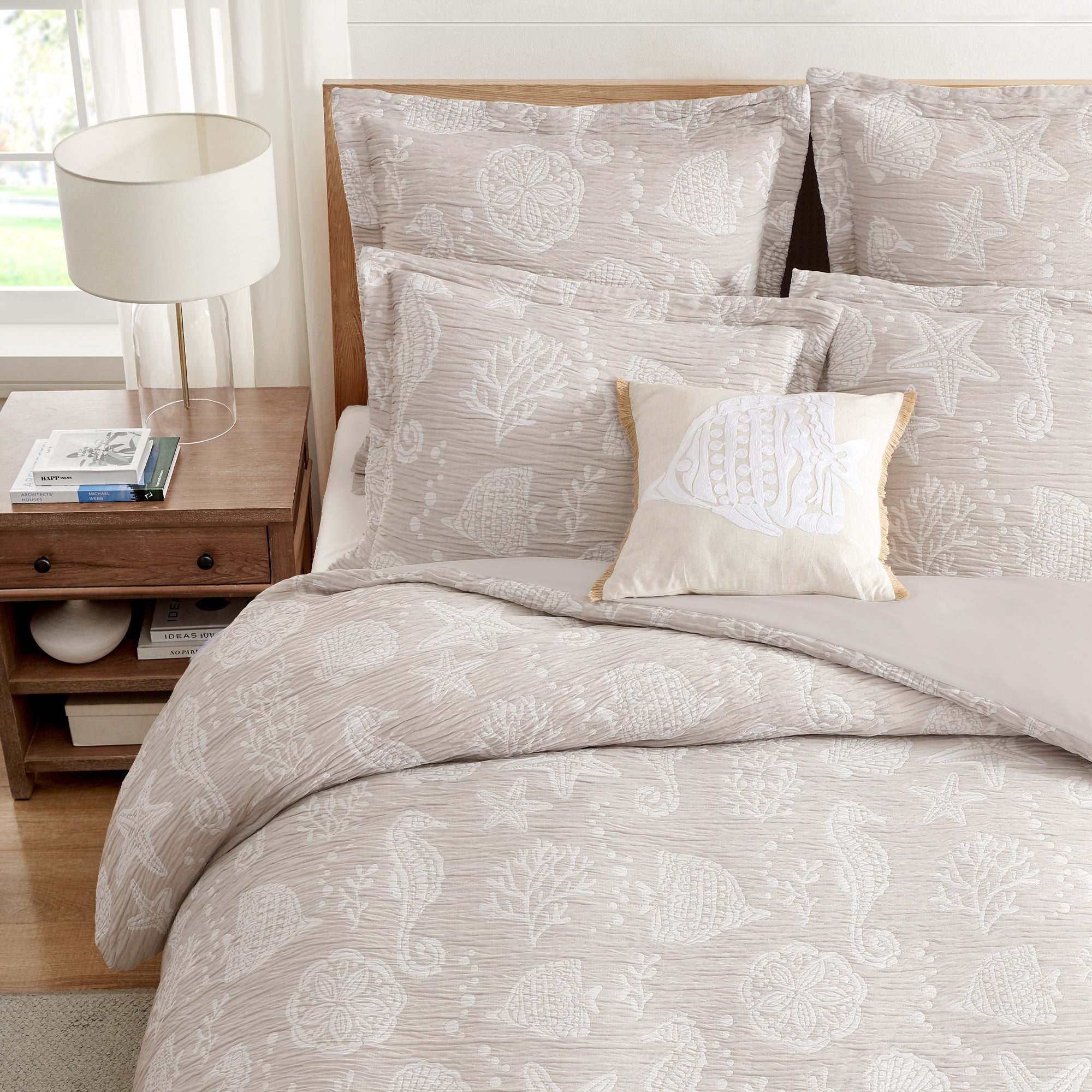 Seaside Charm Crewel Fish Pillow on a beach-themed bedding set with seashells and ocean embroidery.
