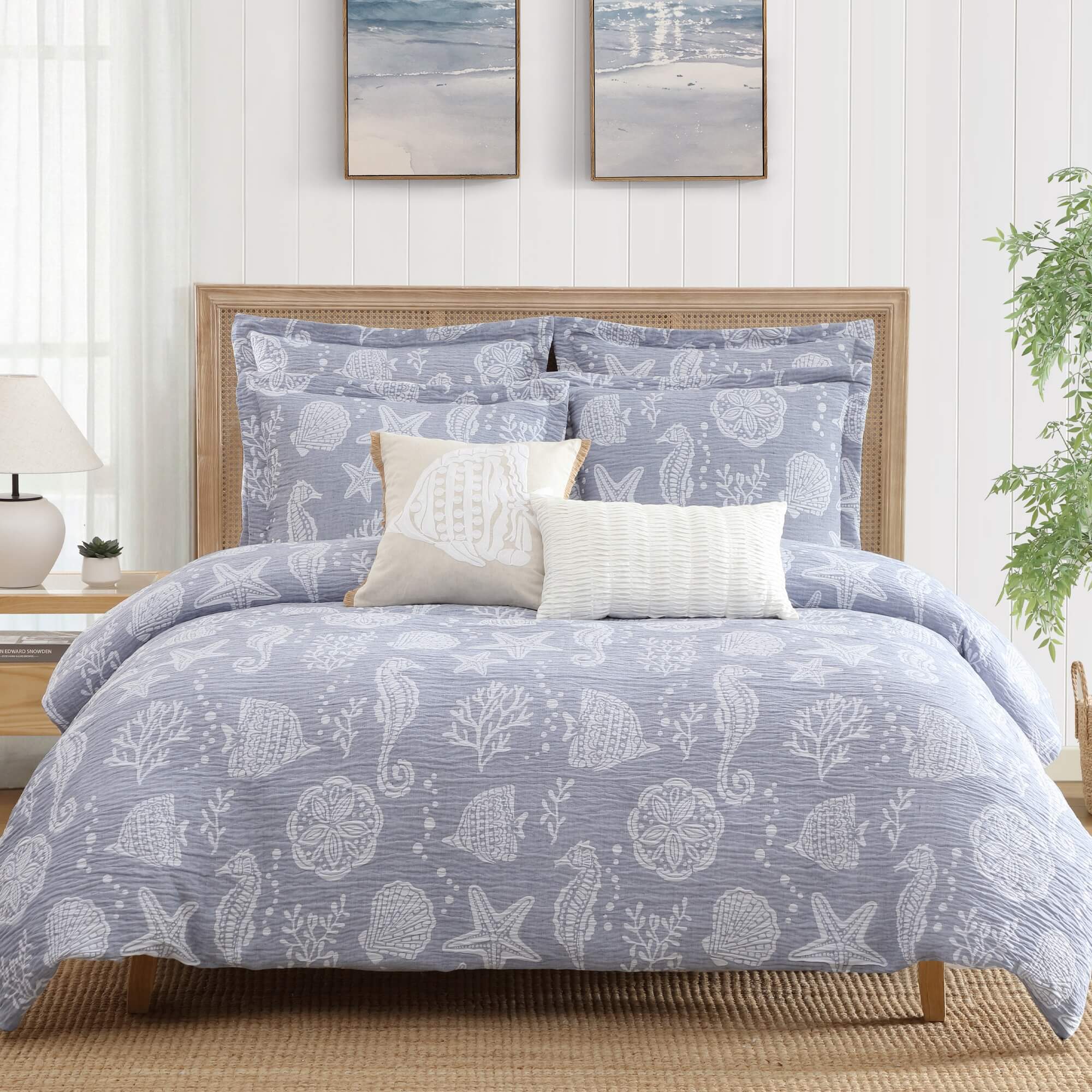 A bed with blue sea motif bedding set and white pillows in a bedroom setting.
