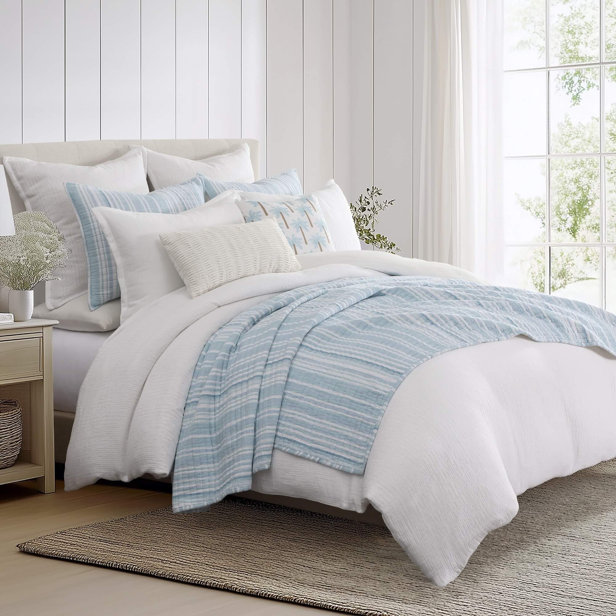 Bedroom with a neatly made bed featuring a light blue striped quilt set and white comforter.