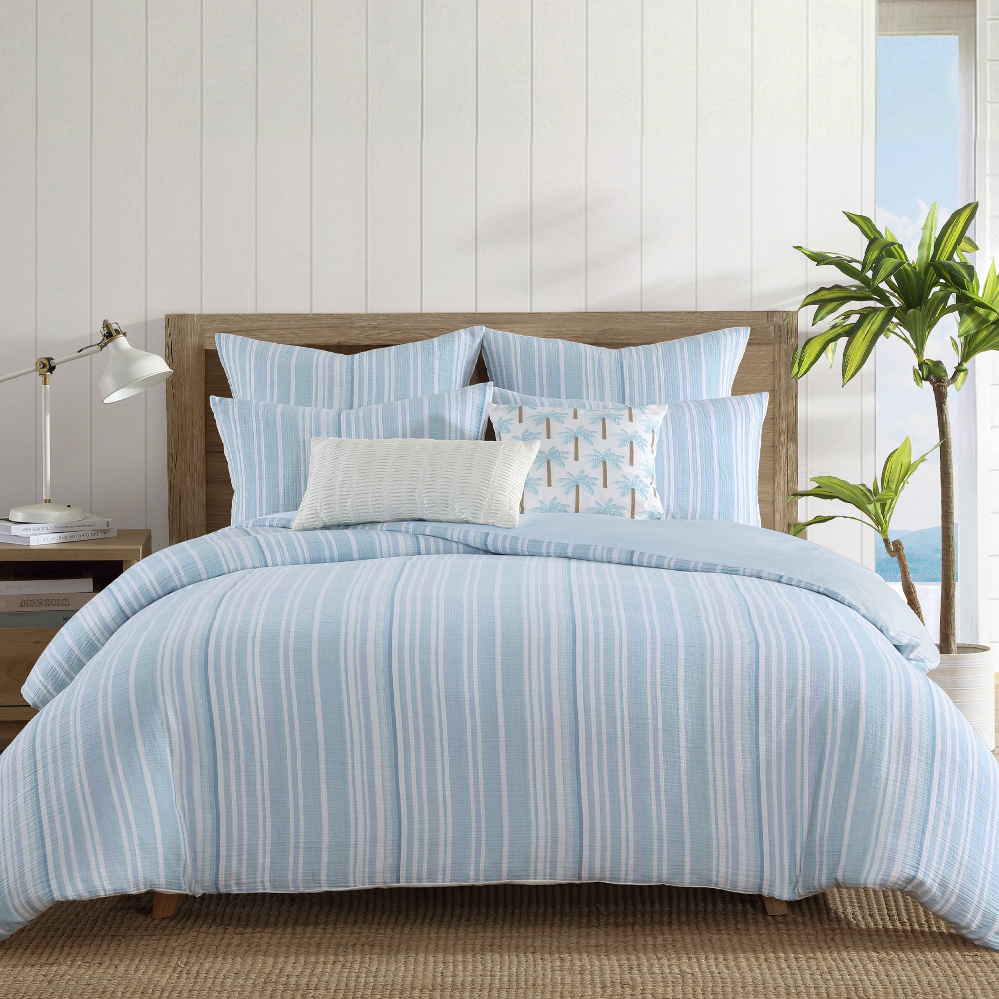 Boracay Stripe Floral Embroidered Pillow showcased on a bed with soft blue striped bedding and decorative pillows.