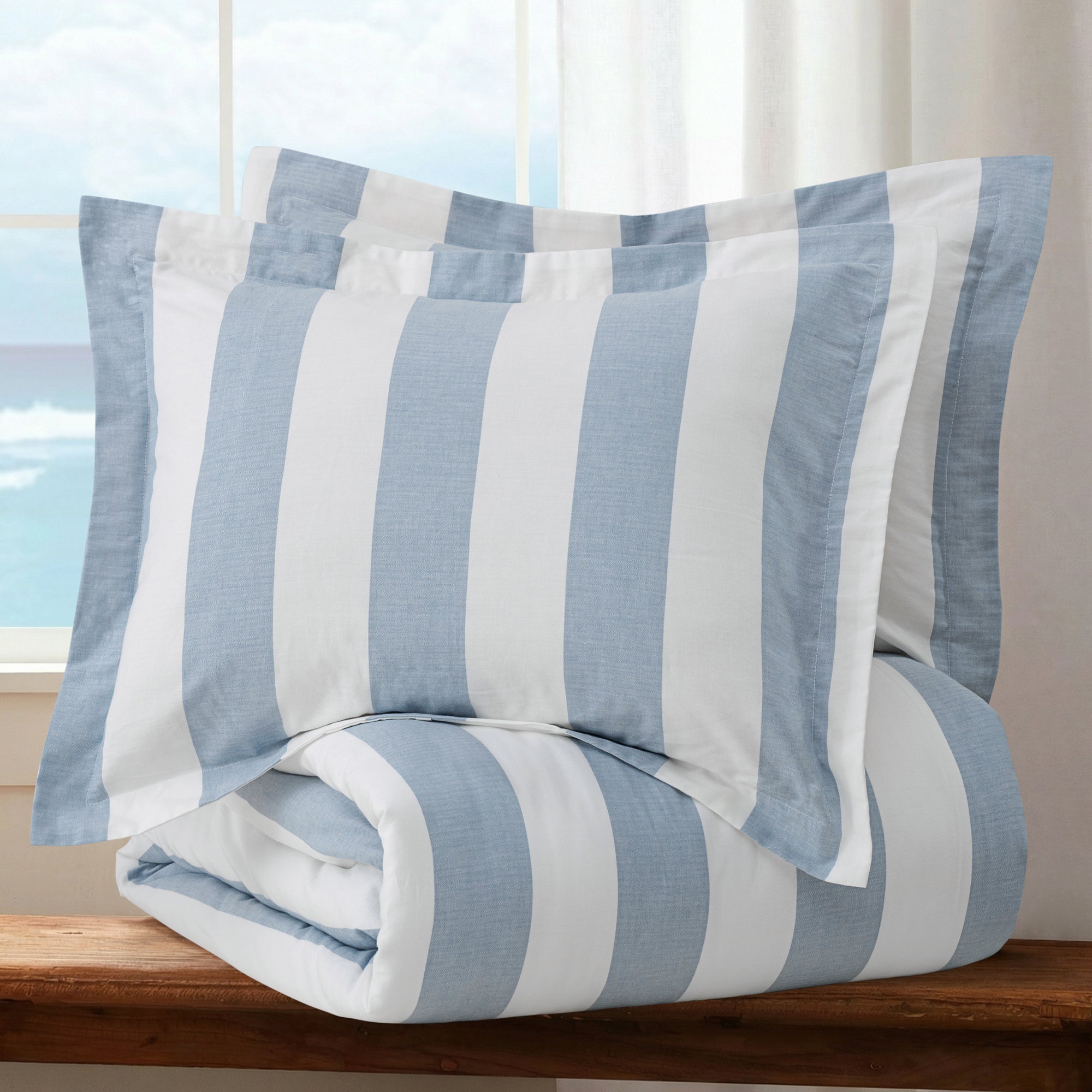 Cabana Woven Stripe Duvet Cover Set featuring blue and white striped duvet and pillow shams, laid on a wooden surface.