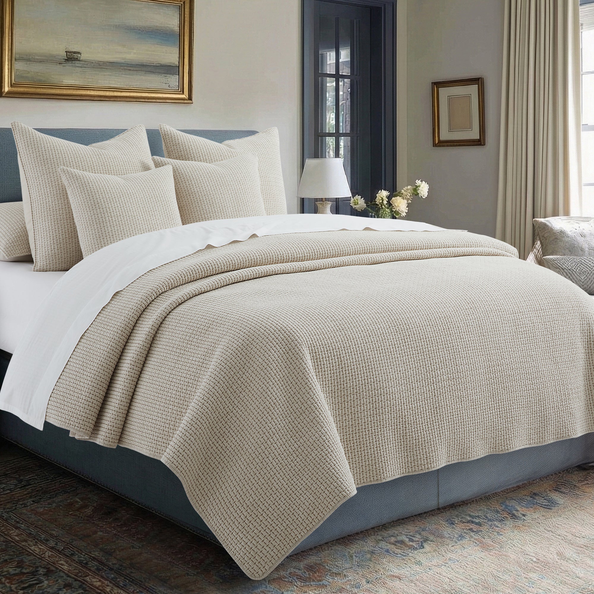 Neatly made bed with beige and white bedding in a bedroom setting.