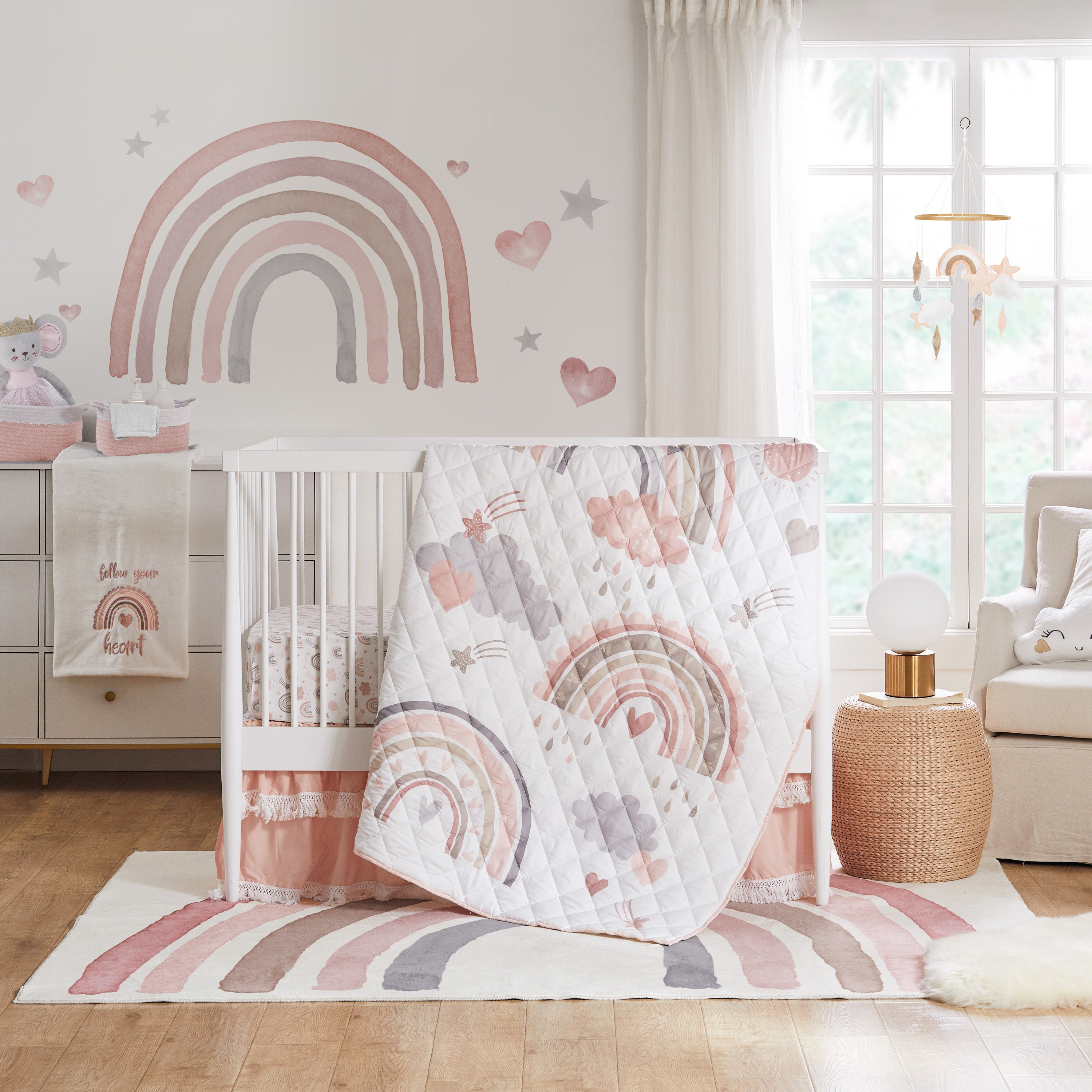 Rainbow-themed baby nursery with white crib, pink and gray bedding, and matching wall decals