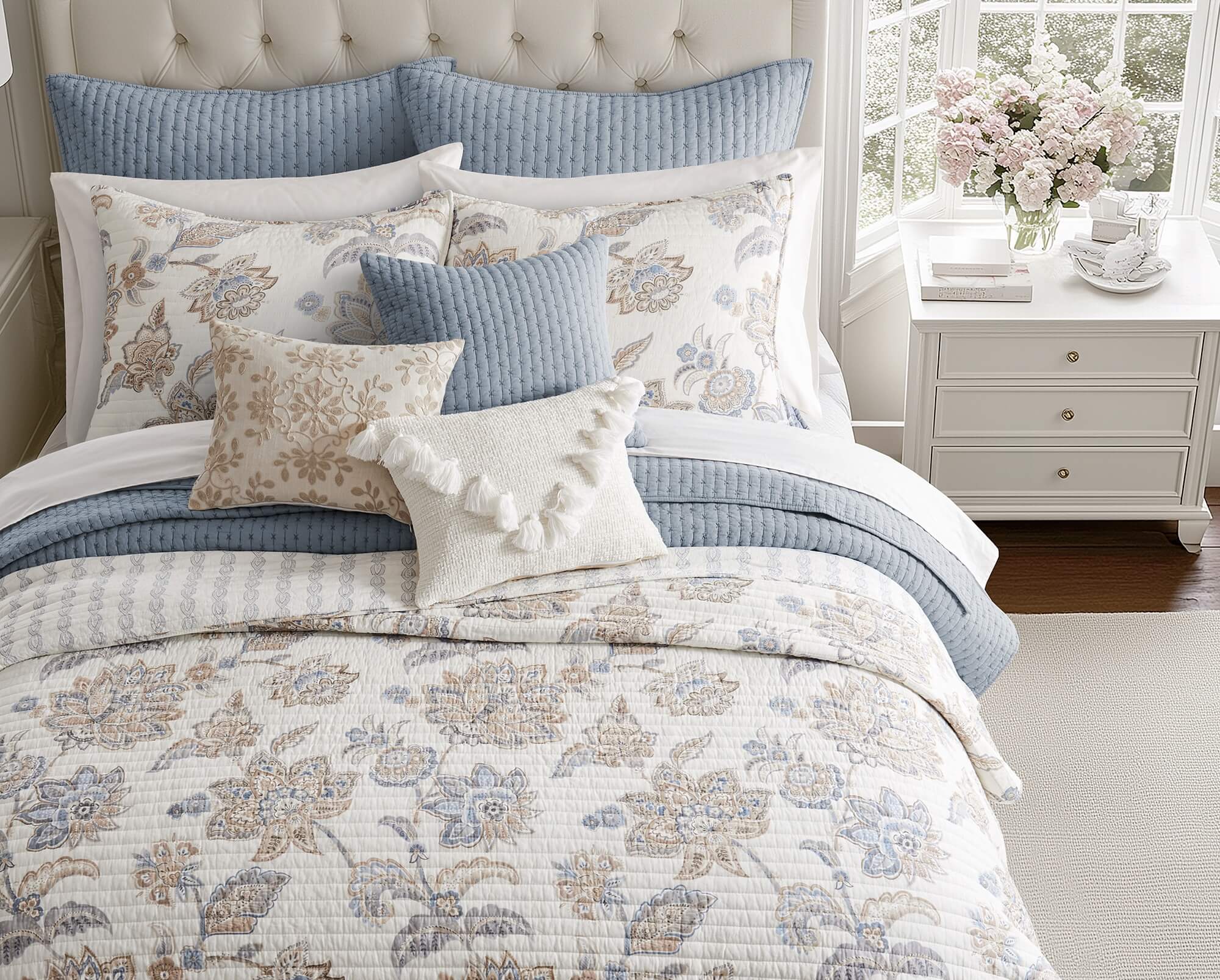 Floral quilt bedding set in soft blue and taupe with layered pillows