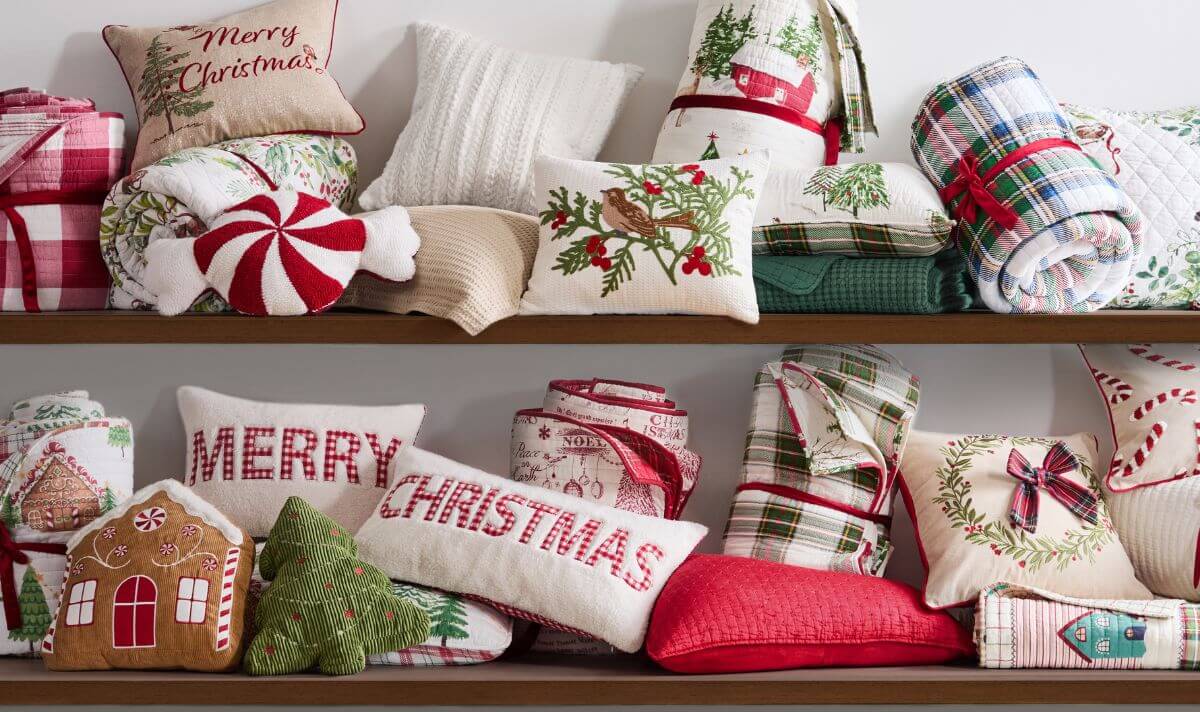 Luxury Christmas bedding arranged on shelves with festive pillows, quilts, and throws in red, green, and white holiday designs