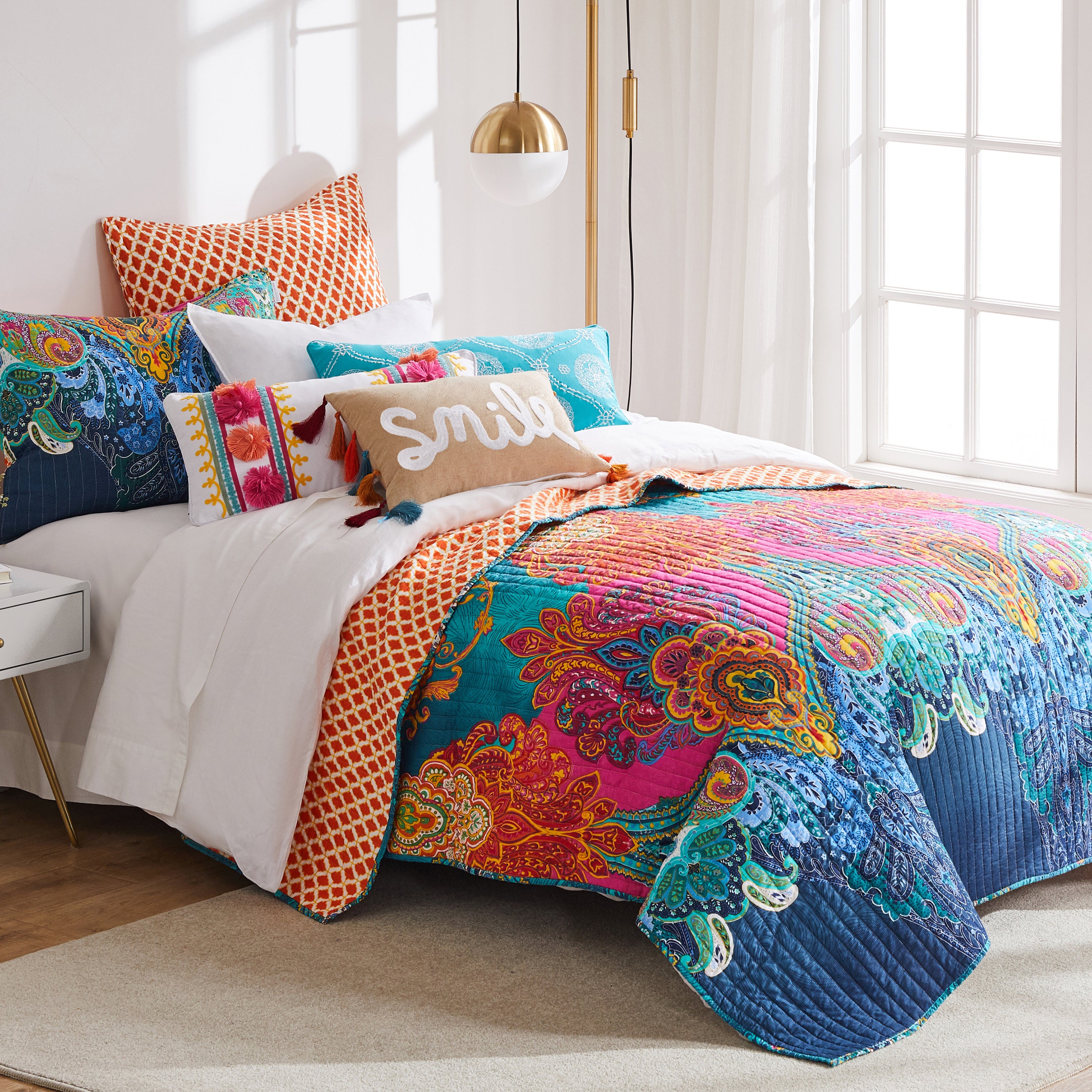 Bohemian bedding set in bright colors layered on a bed