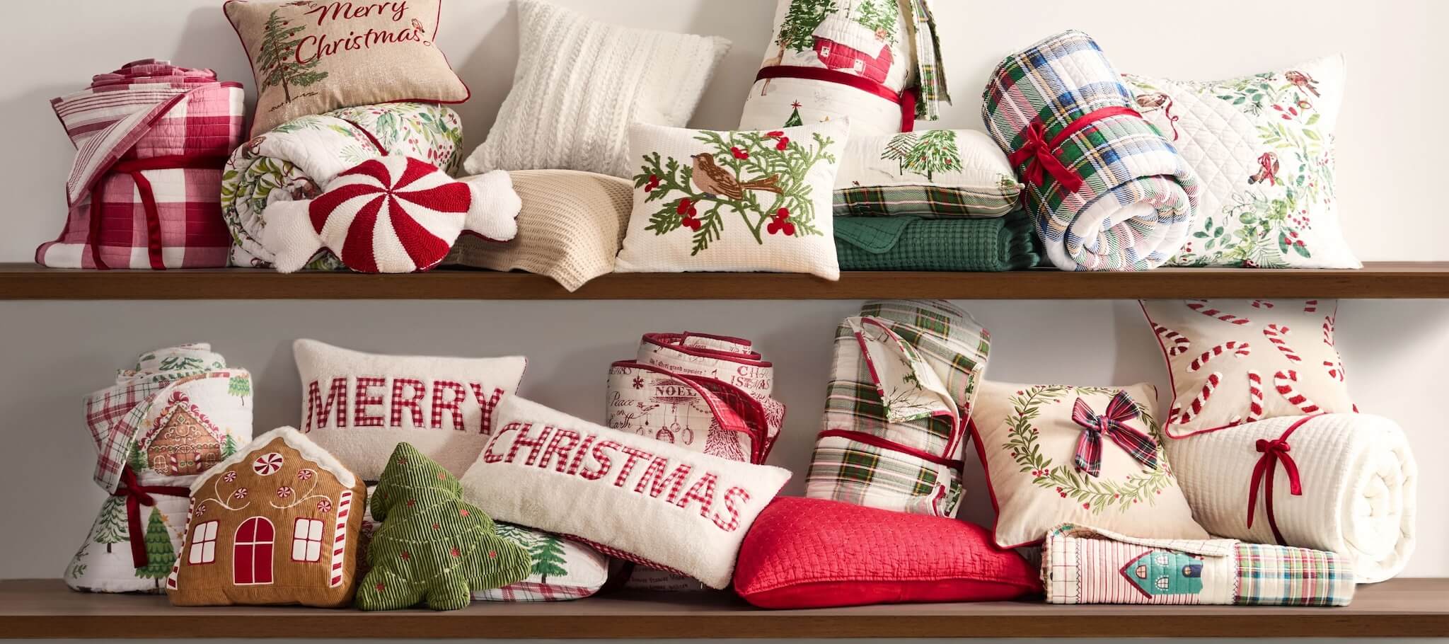 Collection of Christmas-themed pillows and throws on a shelf.