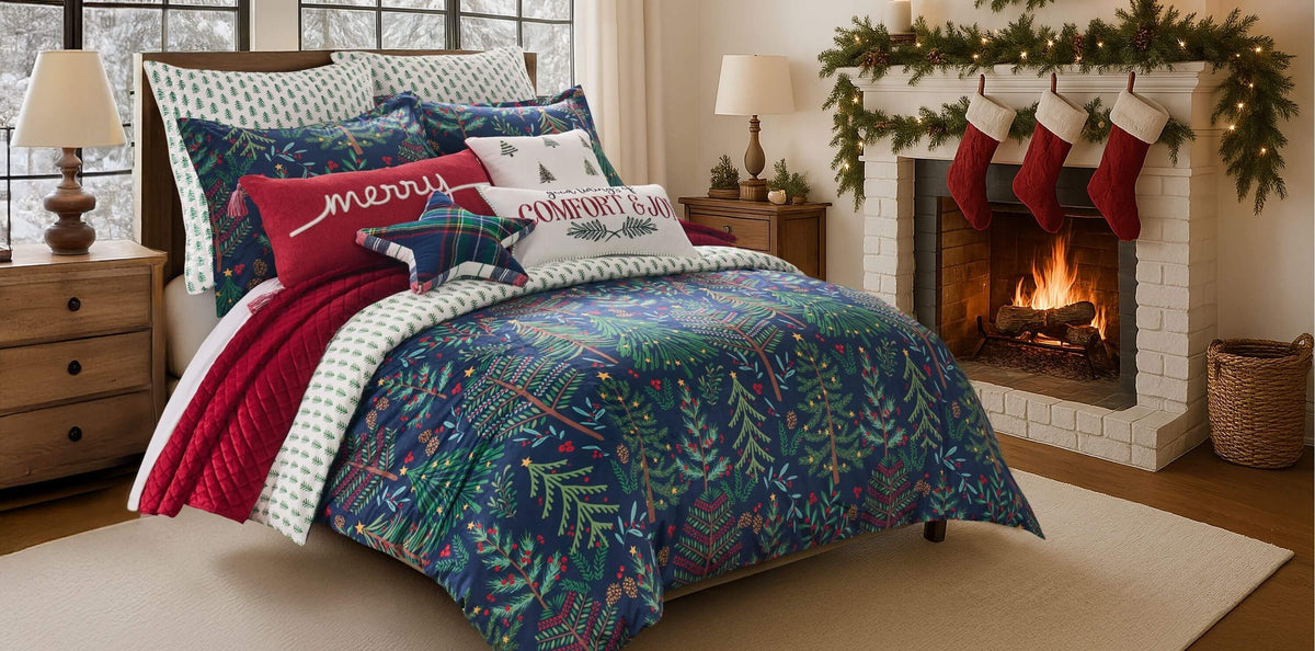 A holiday-themed comforter set featuring a dark blue and green Christmas tree pattern with red accents styled on a bed in a cozy bedroom.