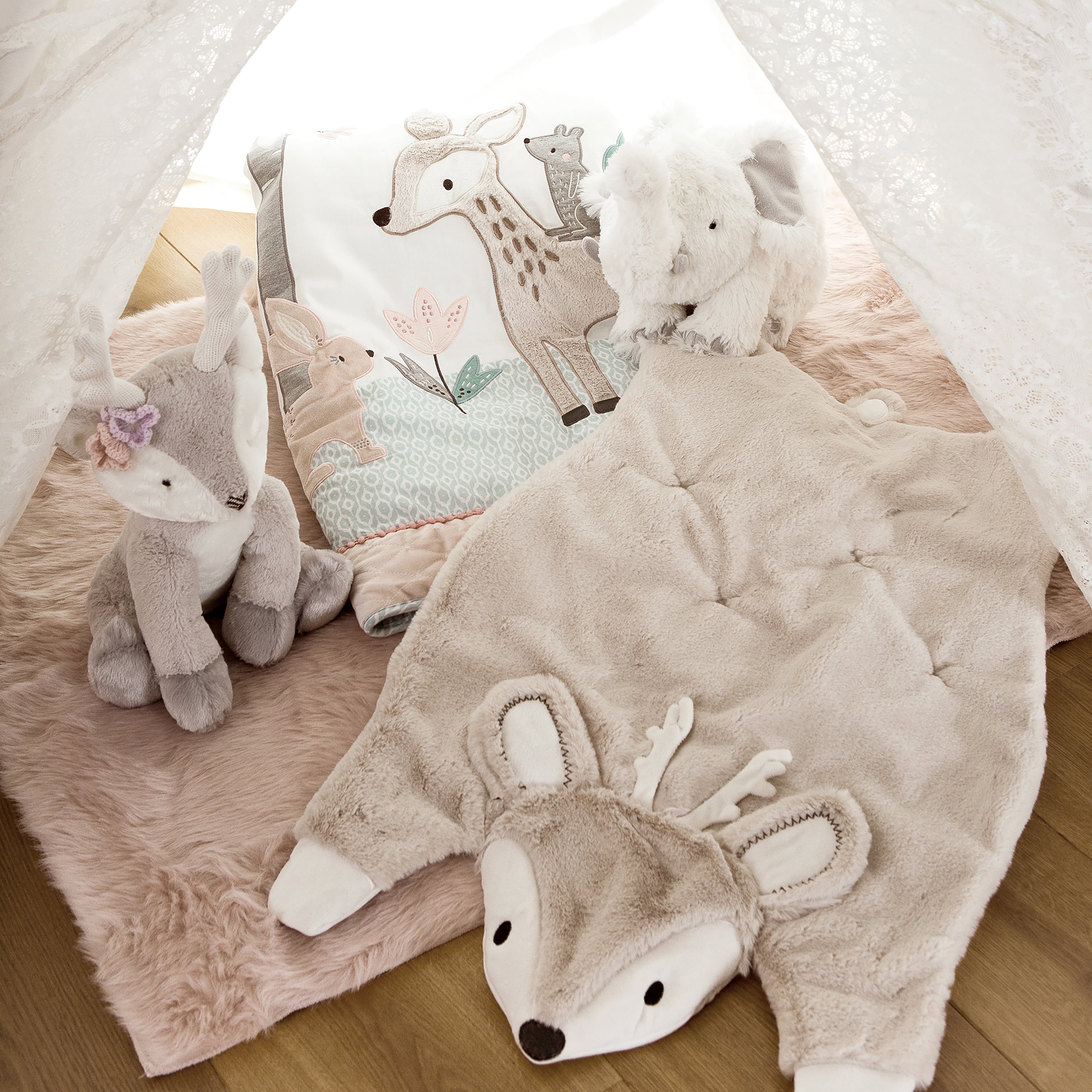 Cozy children's play tent with neutral woodland-themed plush toys, deer blanket, and soft fur rug