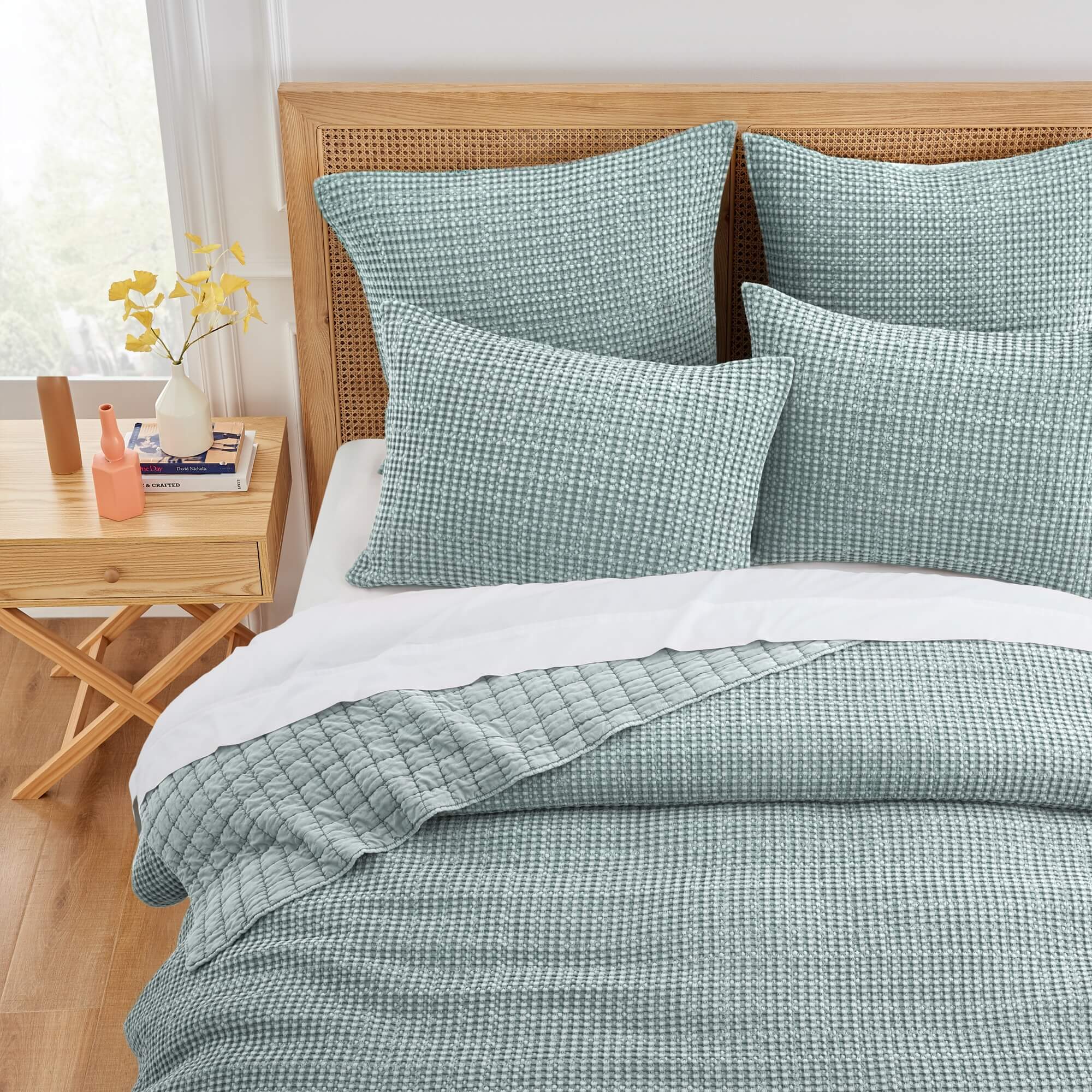 Spa teal waffle textured bedding set styled on a bed with a wooden headboard and matching side table.