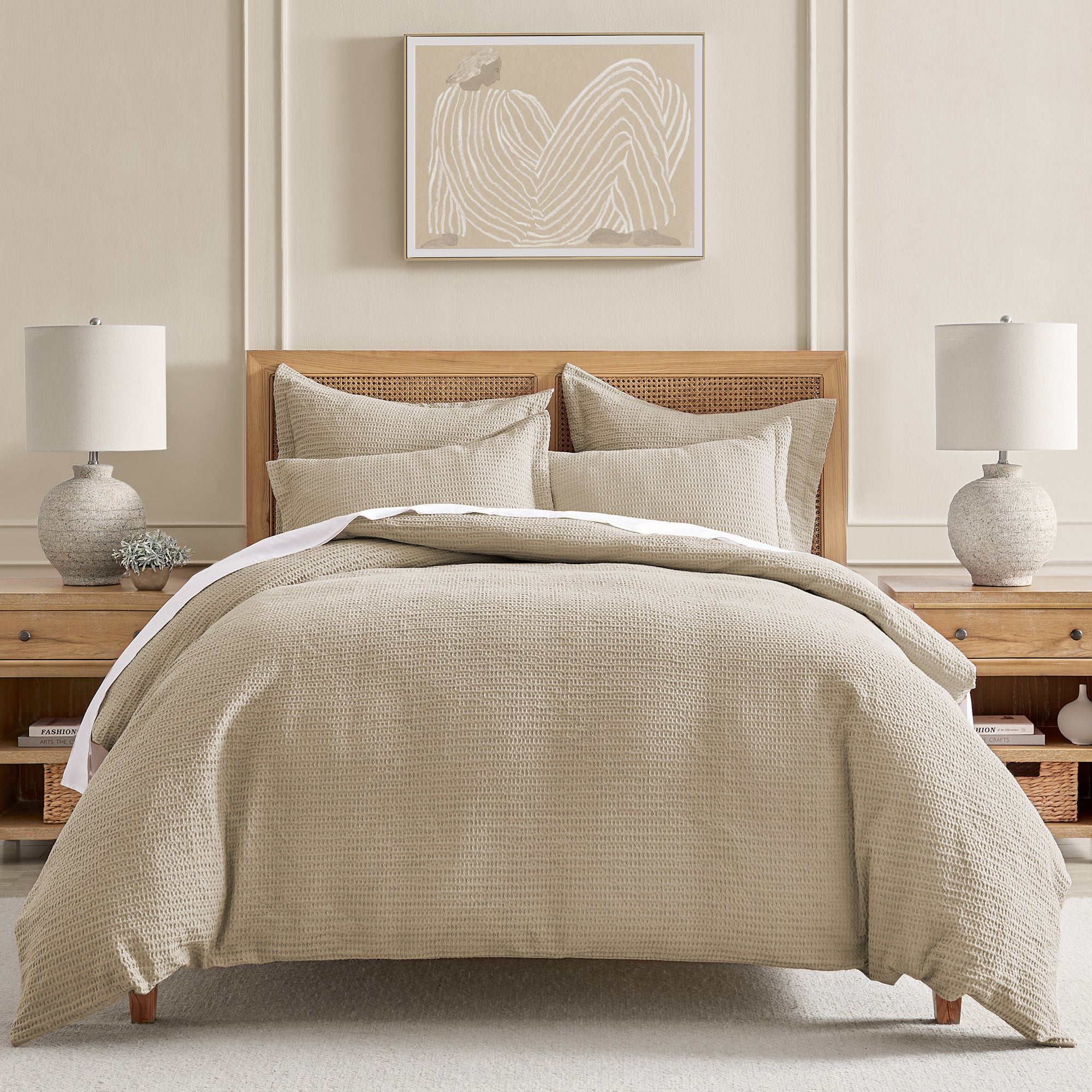 Beige textured comforter on a bed in a bedroom setting with lamps and decor.