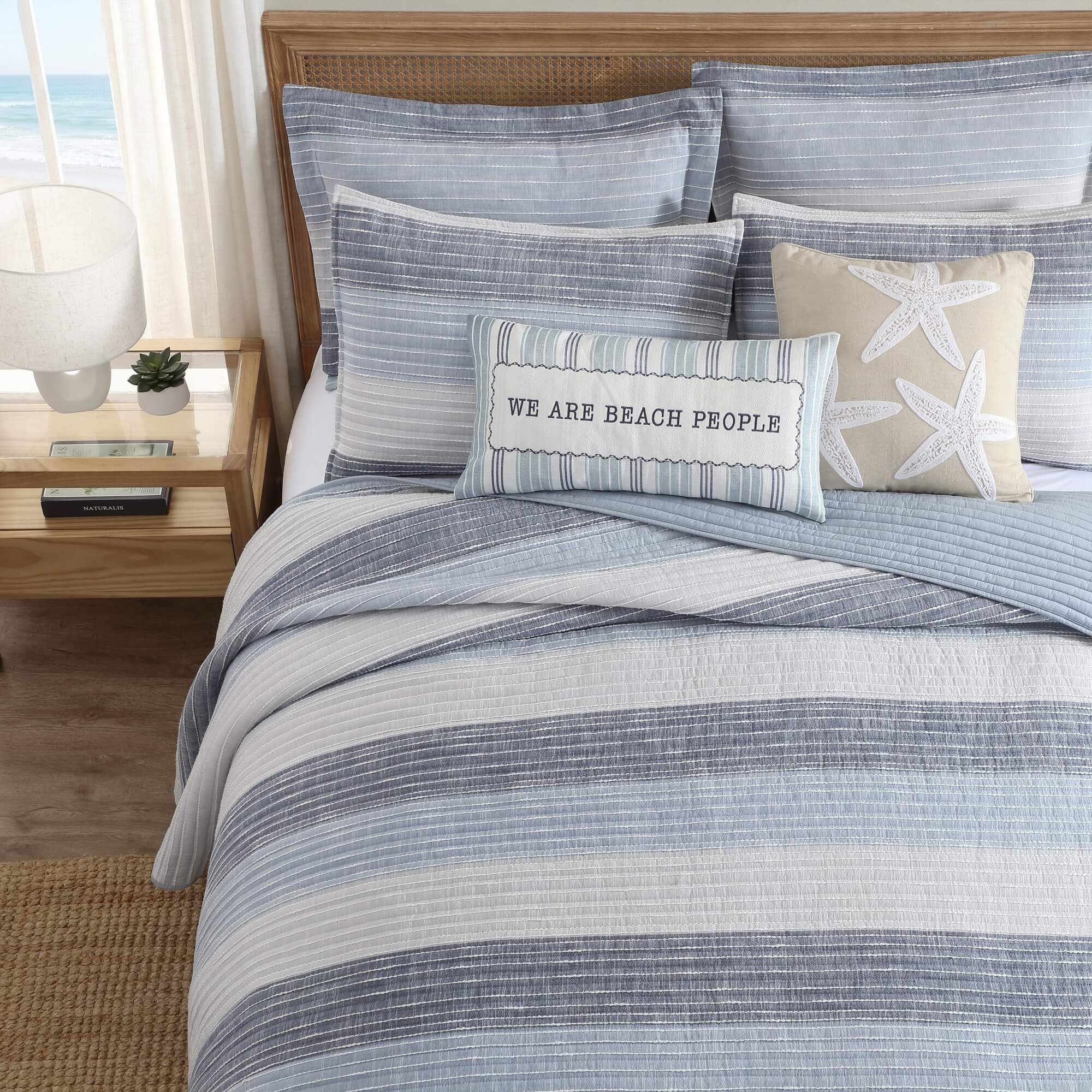Bed with striped bedding and decorative pillows in a bedroom setting.