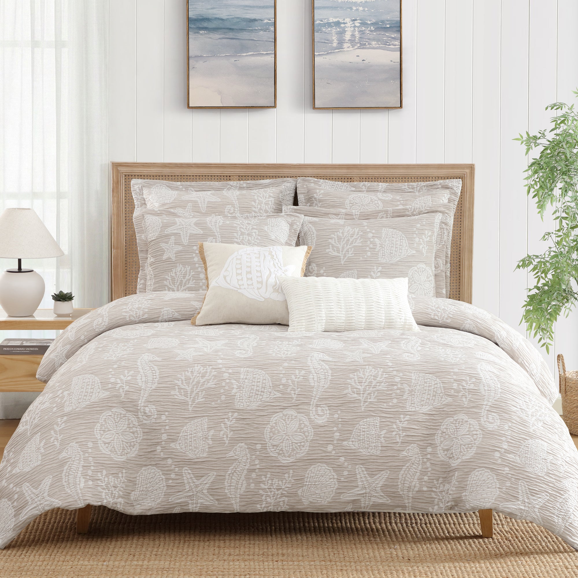 Seaside Charm Crewel Fish Pillow on a light beige bedding with coastal patterns and soft textures.
