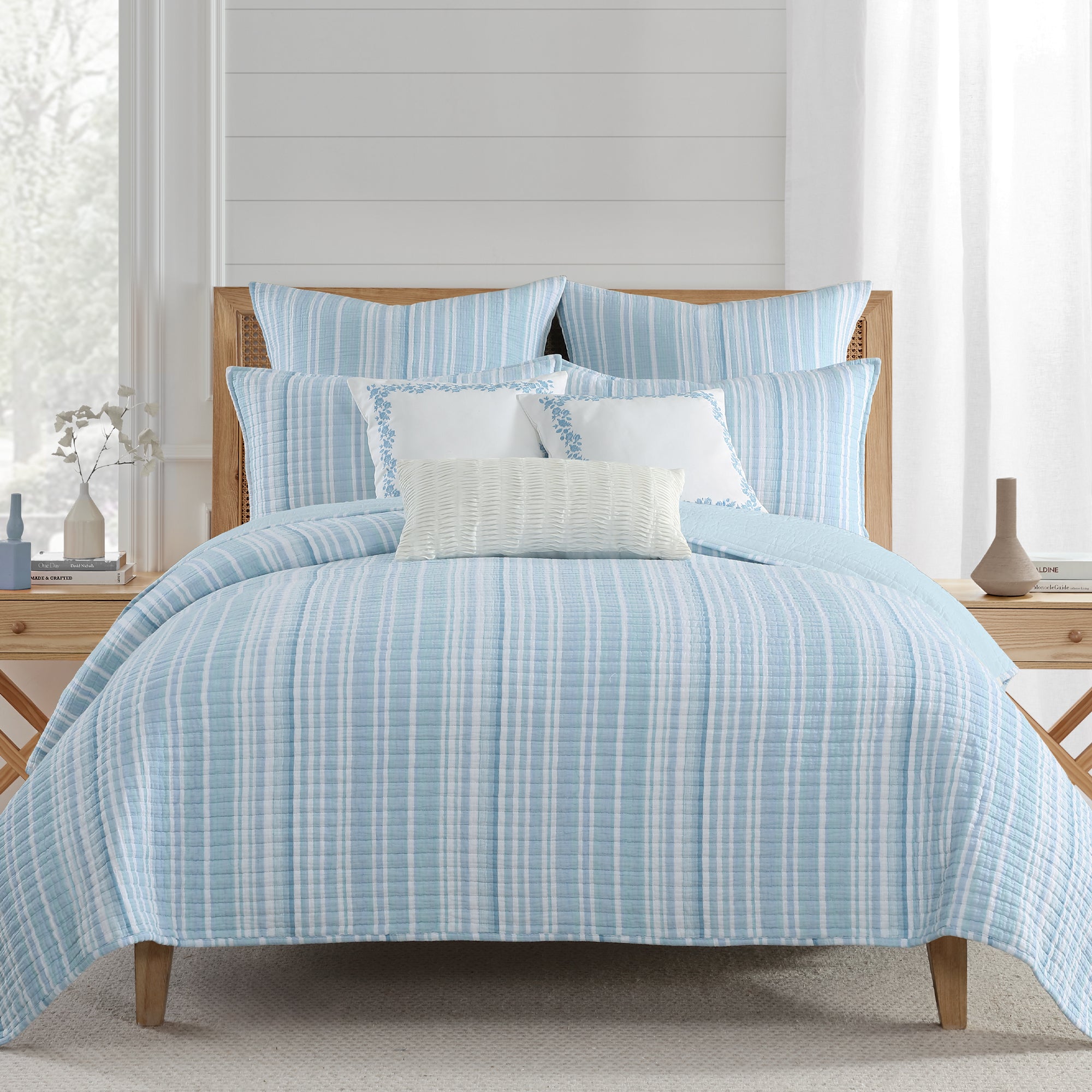 Boracay Stripe Crewel Palm Tree Pillow on a blue and white bedding set in a bright, cozy bedroom setting.