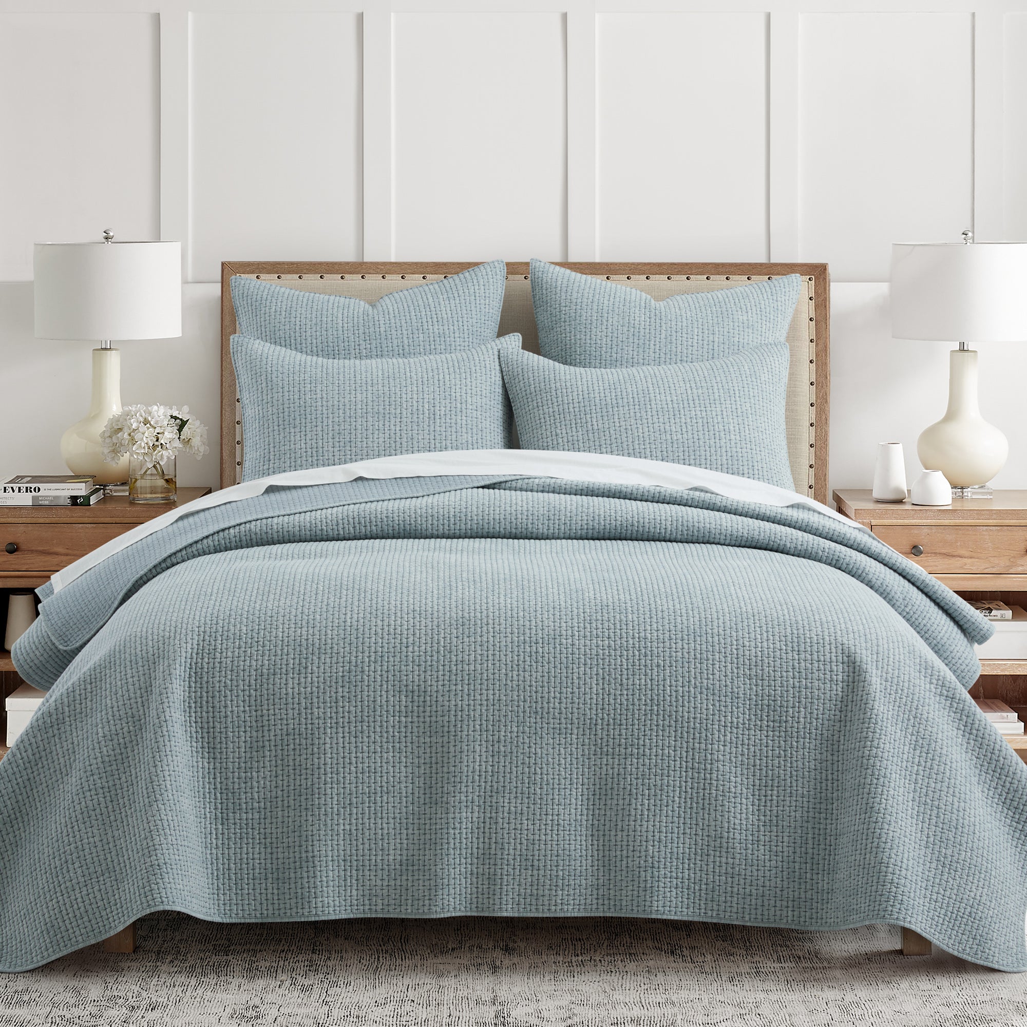 Blue checkered quilt and pillow set on a bed in a bedroom setting.