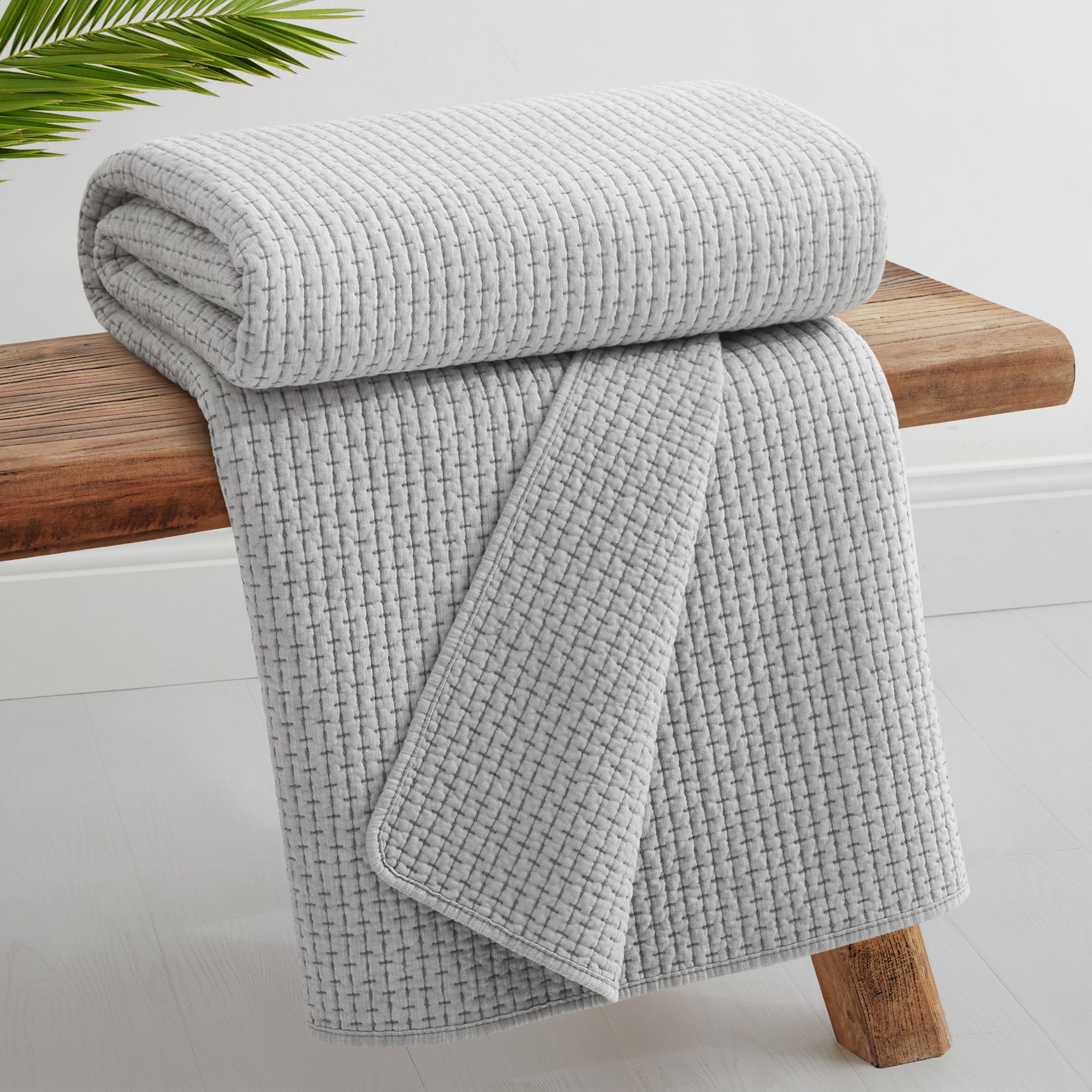 Pick-Stitch Artisan Quilted Throw draped over a wooden bench, showcasing its textured, cozy design.