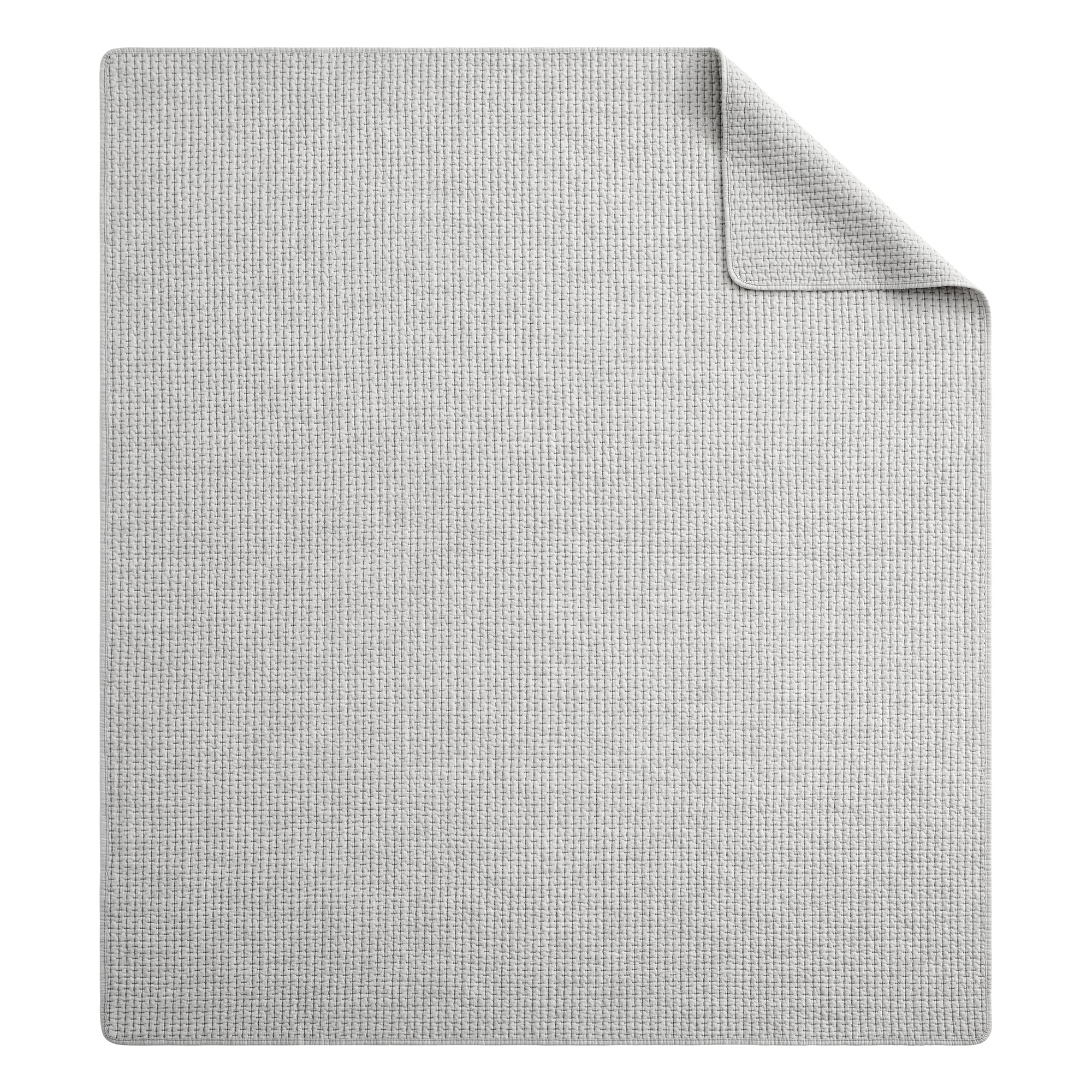 Pick-Stitch Artisan Quilted Throw displaying a textured light gray quilted surface with a folded corner.
