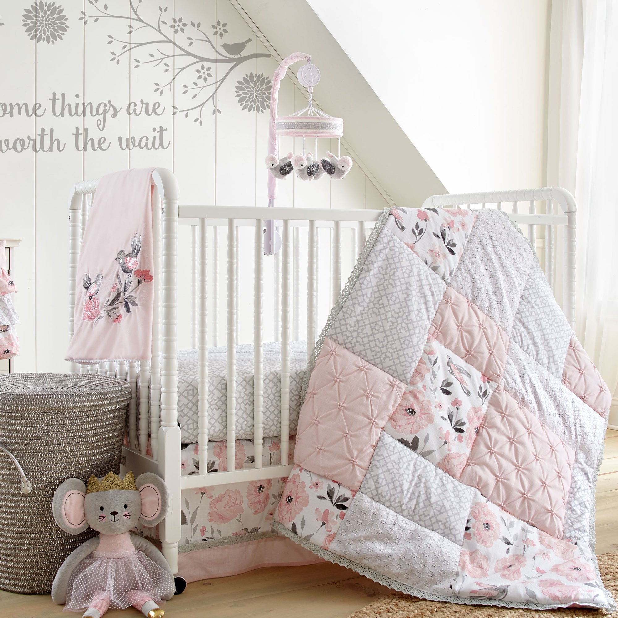 Floral-themed nursery featuring white crib, pink and white patchwork floral-themed bedding set, and matching decor