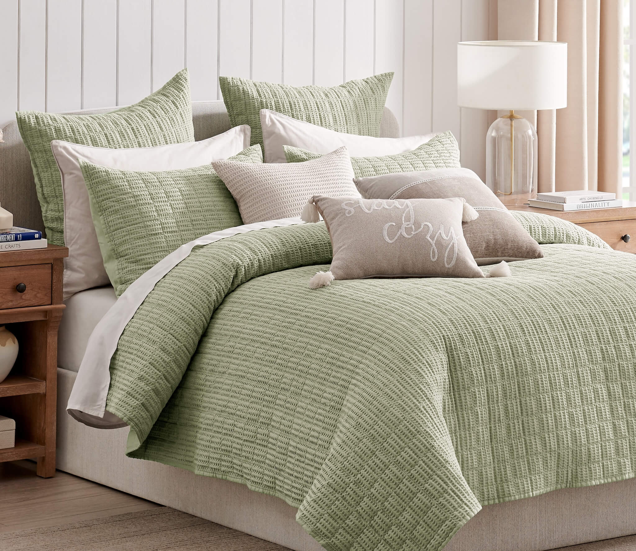 Green textured bedding set on a bed with matching pillows in a bedroom setting.