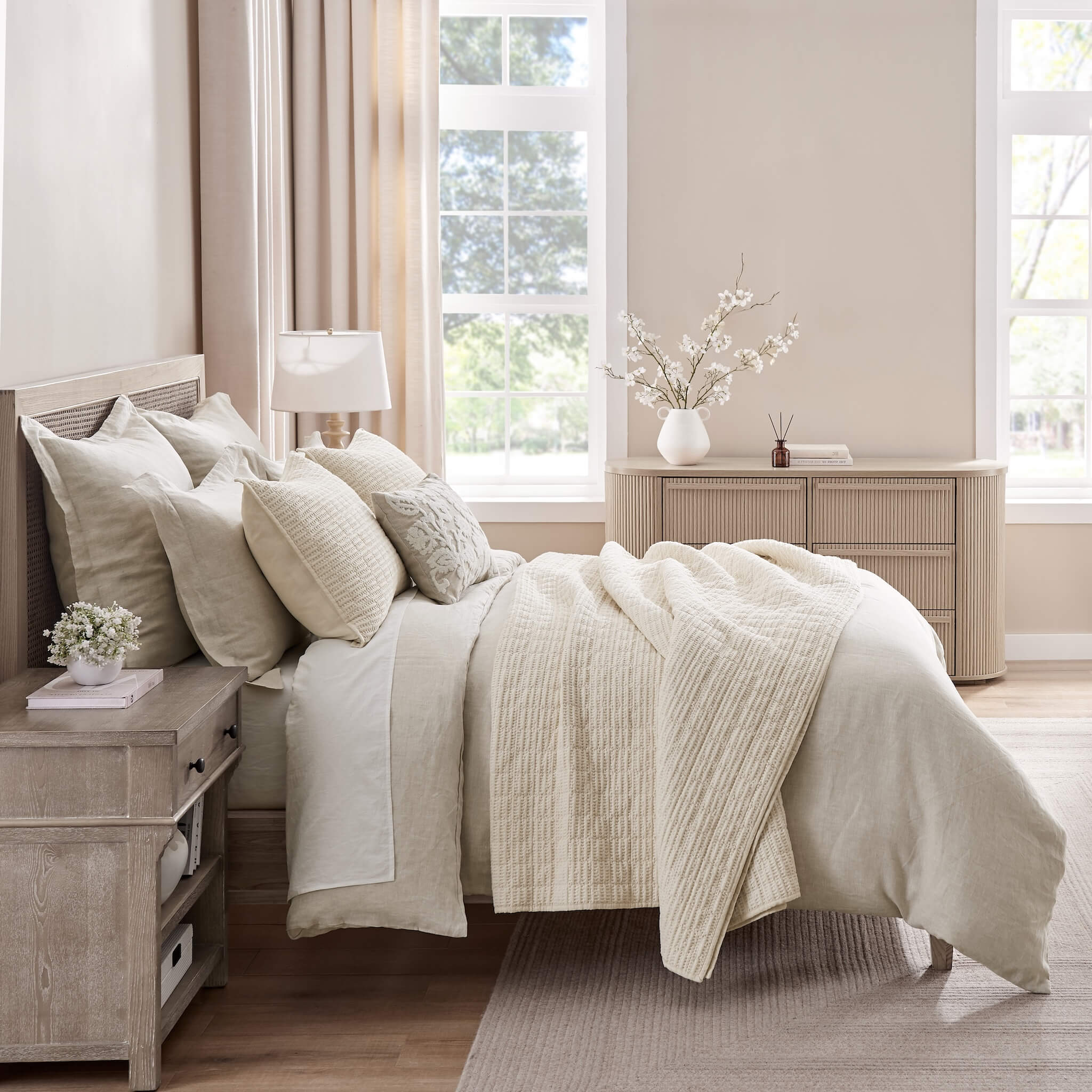 Neatly made bed with beige bedding in a bright bedroom