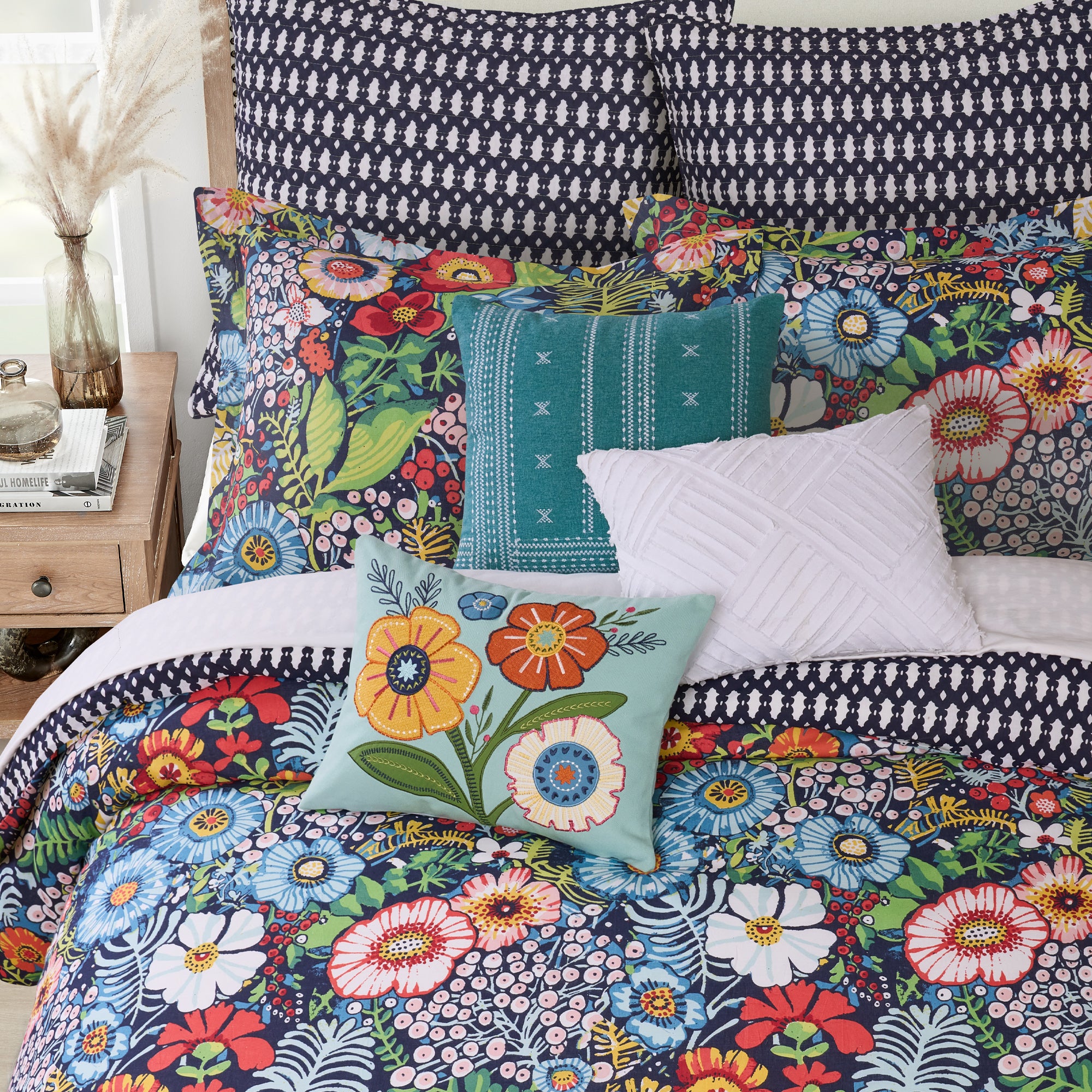 Colorful floral bedding set with decorative pillows on a bed.