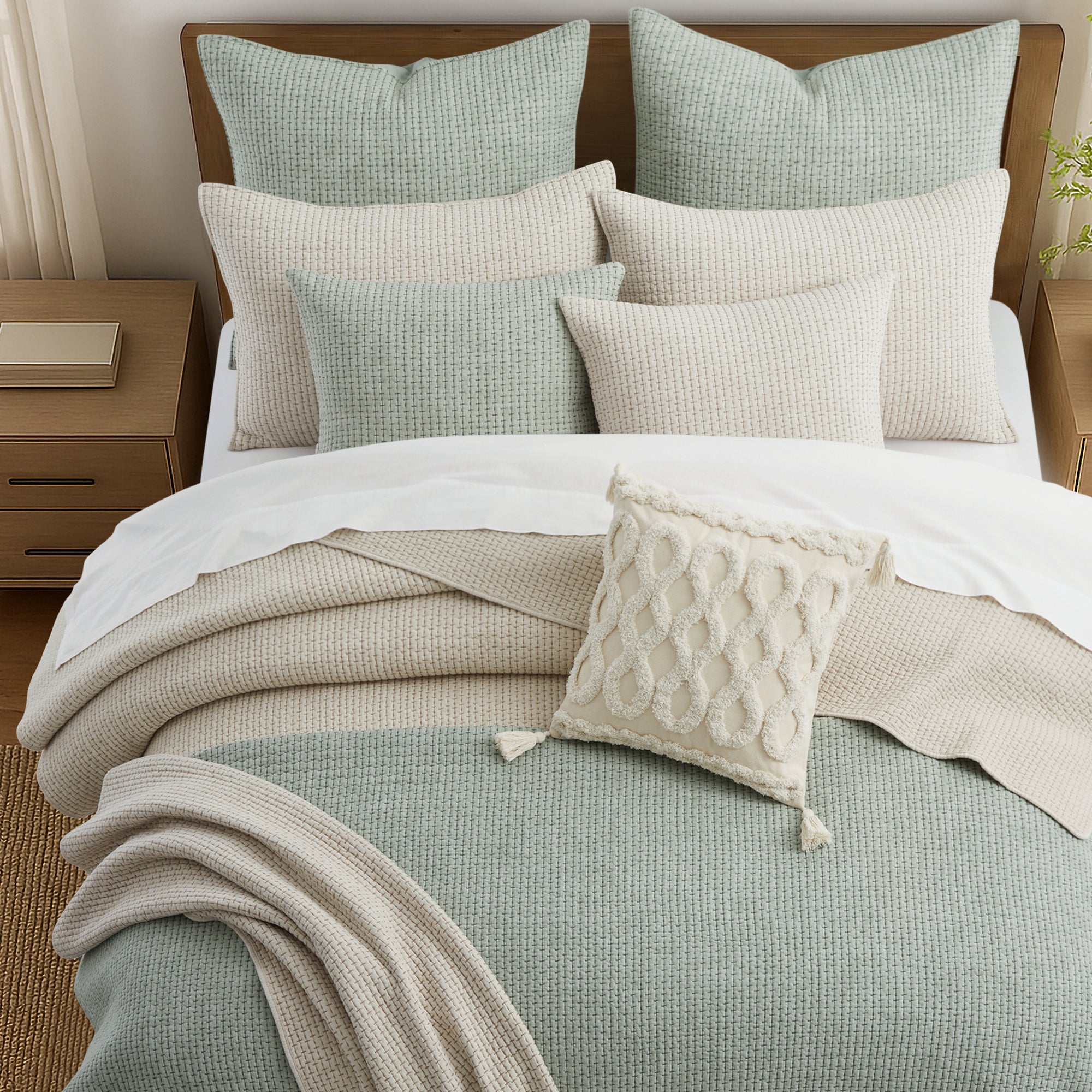 Neatly made bed with various pillows and a blanket in a bedroom setting.