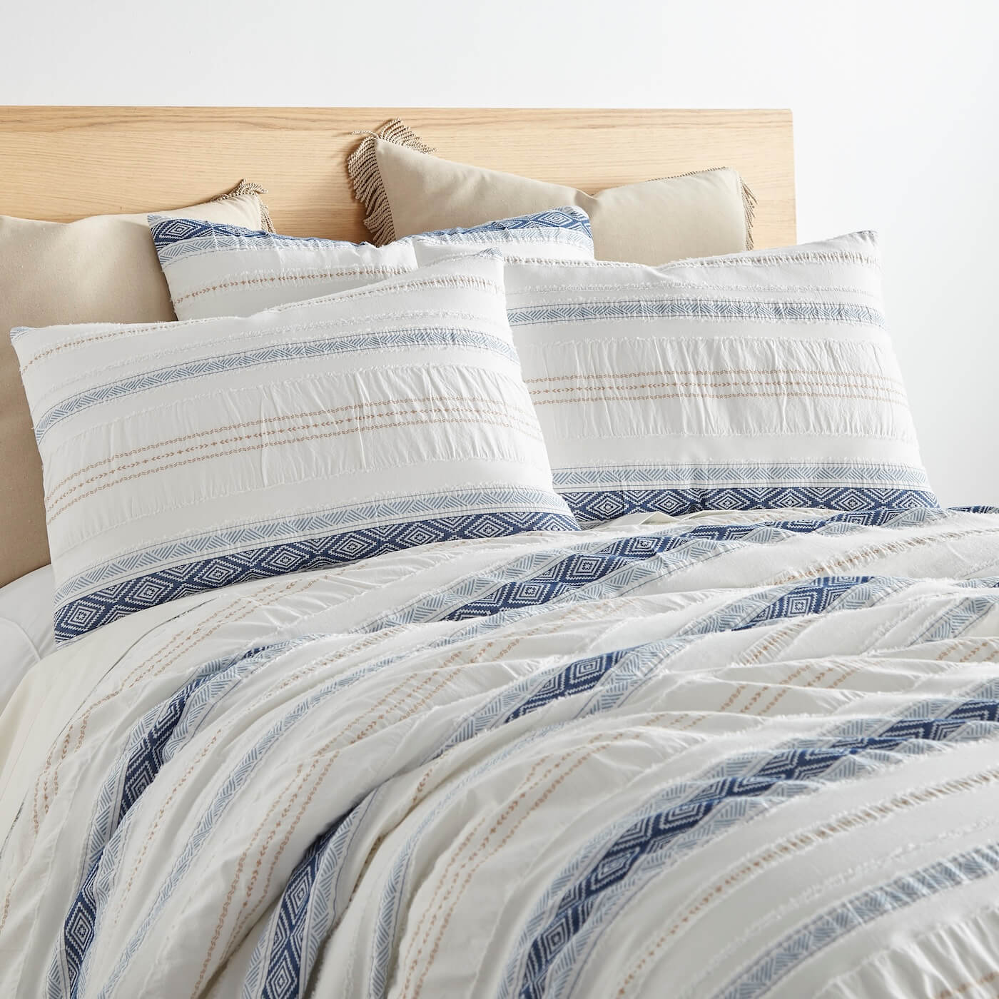 Bed with white and blue striped bedding and pillows against a light background