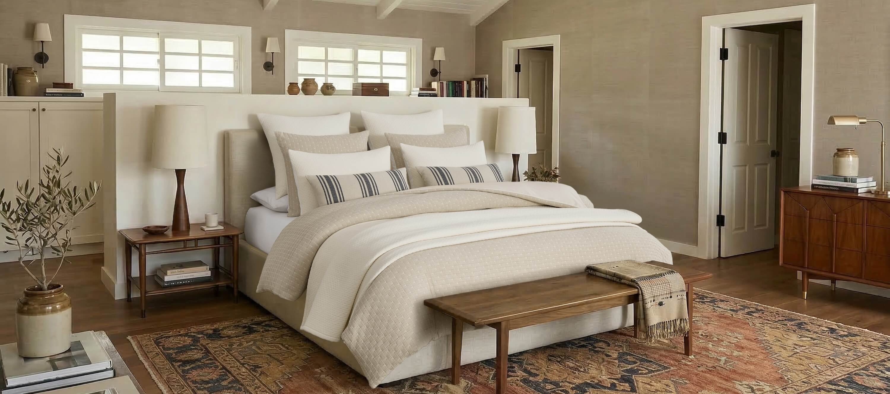 Neatly made bed fully styled with Levtex Home bedding and decor, featuring a quilt and a comforter layered with shams, decorative pillows, and a throw.