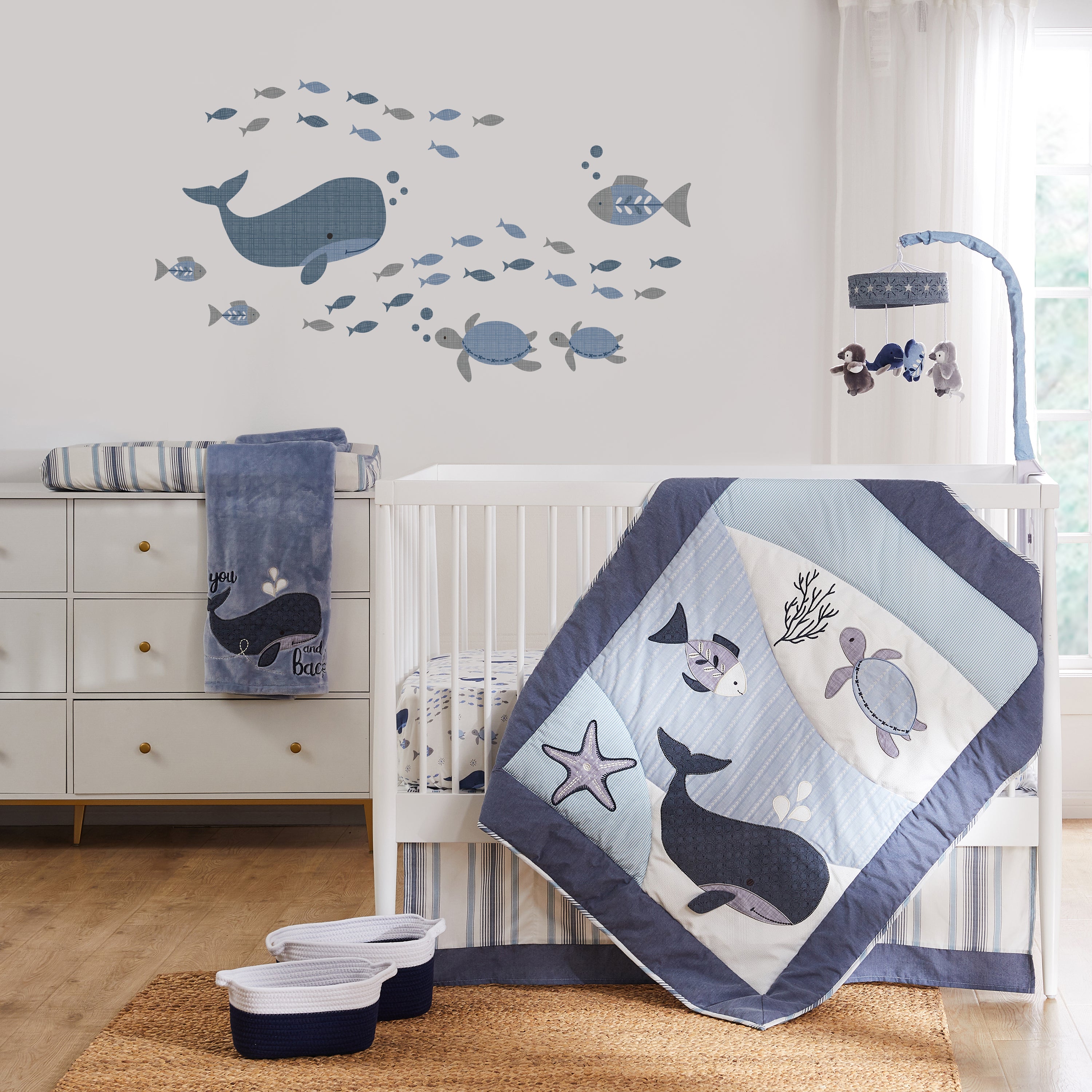Ocean-themed nursery featuring white crib, ocean-themed bedding set, wall decal and matching decor