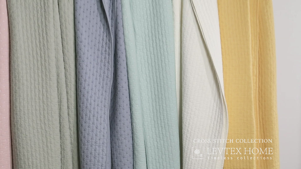 Levtex Home Cross Stitch Collection quilts in pastel colors including pink, green, blue, white, and yellow, showing textured cross-stitch patterns.