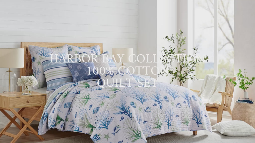 Video with a  bed styled with a blue and white quilt set featuring coastal motif prints and overlayed text "Harbor Bay Collection 100% Cotton Quilt Set"
